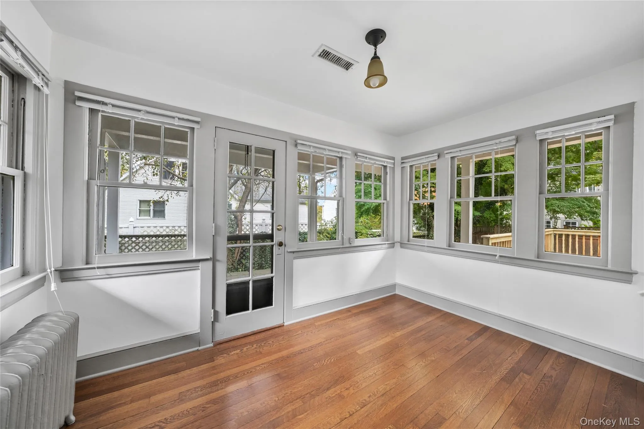 Unfurnished sunroom with radiator heating unit and hardwood / wood-style floors Unfurnished sunroom with radiator heating unit and hardwood / wood-style floors