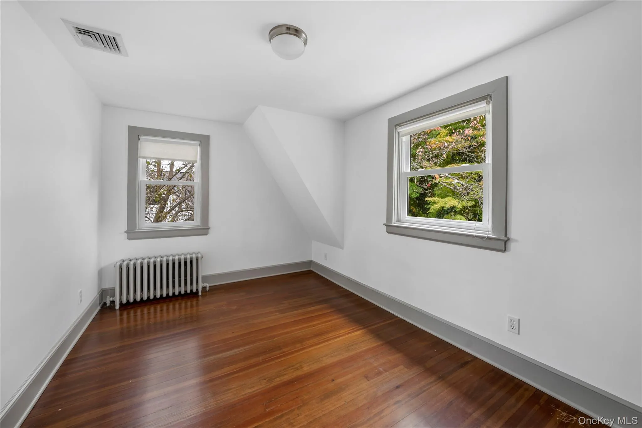 Additional living space with radiator heating unit and dark wood finished floors Additional living space with radiator heating unit and dark wood finished floors