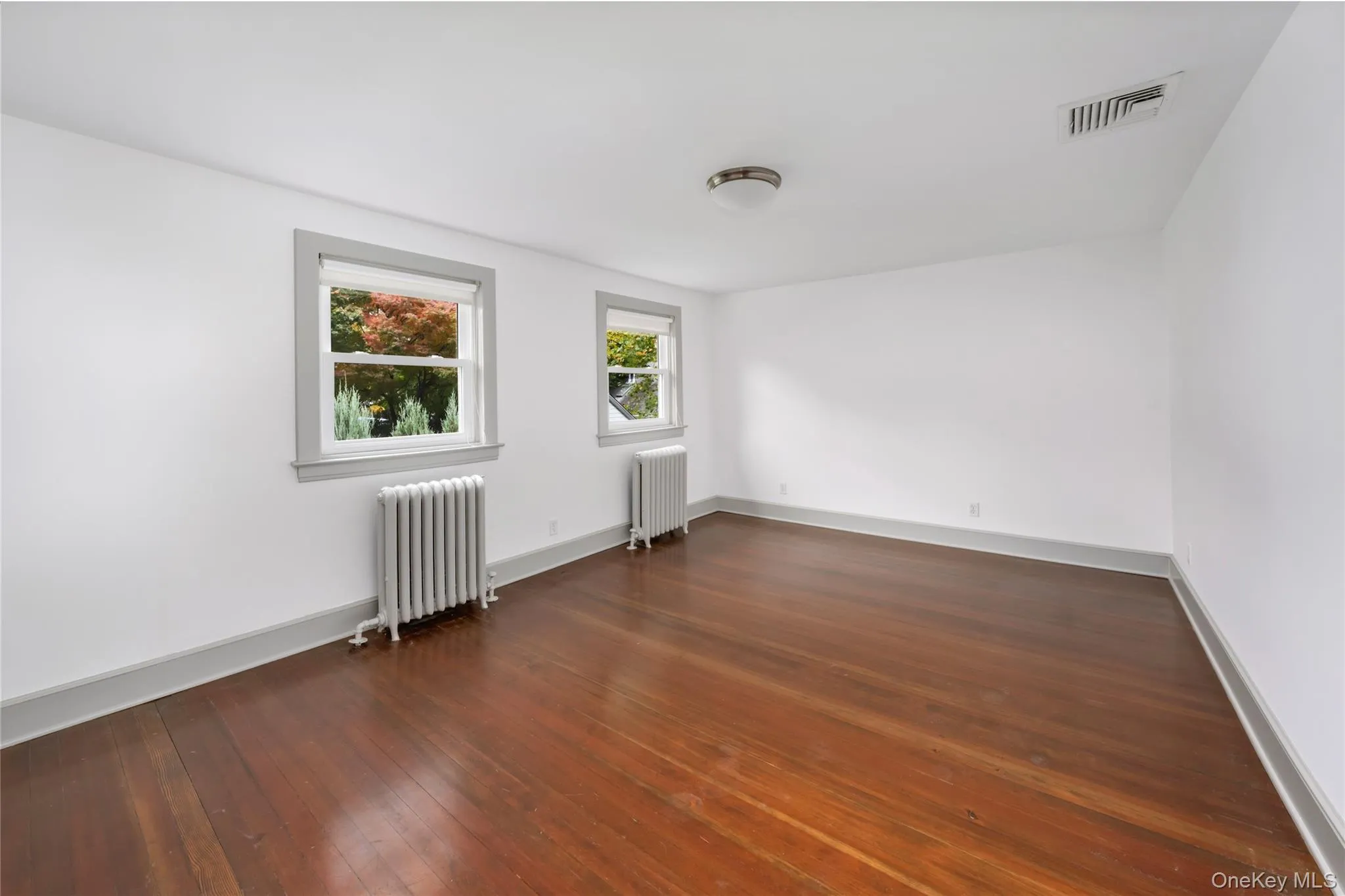 Unfurnished room with radiator and dark wood-type flooring Unfurnished room with radiator and dark wood-type flooring