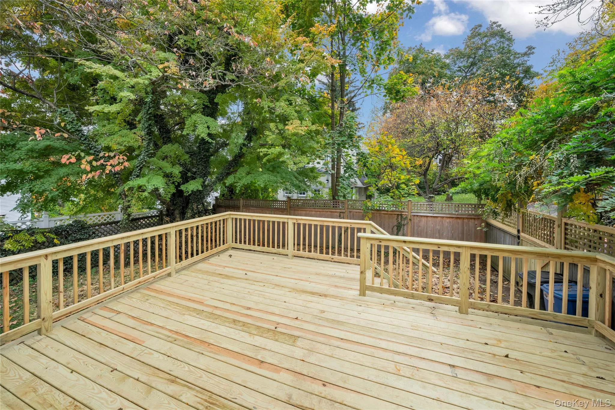Wooden deck featuring a fenced backyard and view of scattered trees Wooden deck featuring a fenced backyard and view of scattered trees