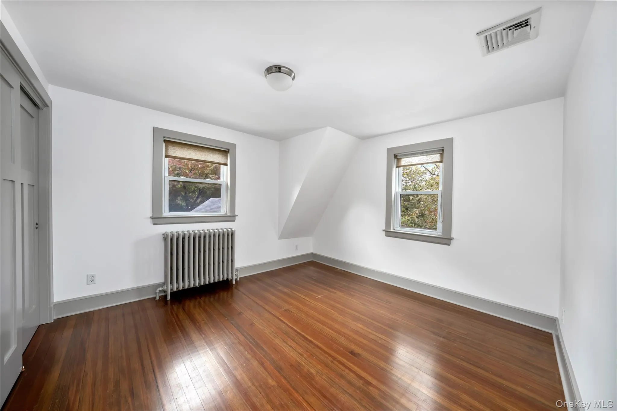 Additional living space featuring radiator and dark wood-style floors Additional living space featuring radiator and dark wood-style floors