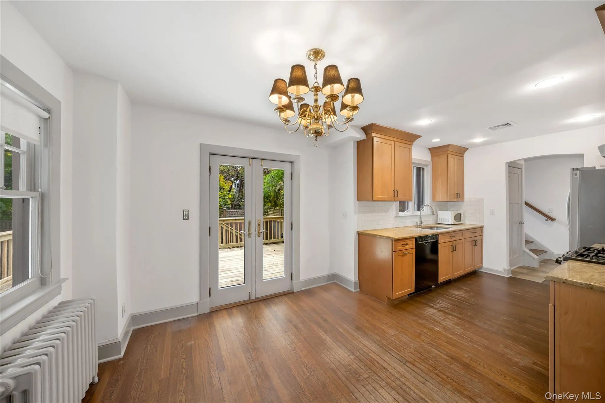 Kitchen featuring radiator, backsplash, french doors, freestanding refrigerator, and dark wood-style floors Kitchen featuring radiator, backsplash, french doors, freestanding refrigerator, and dark wood-style floors
