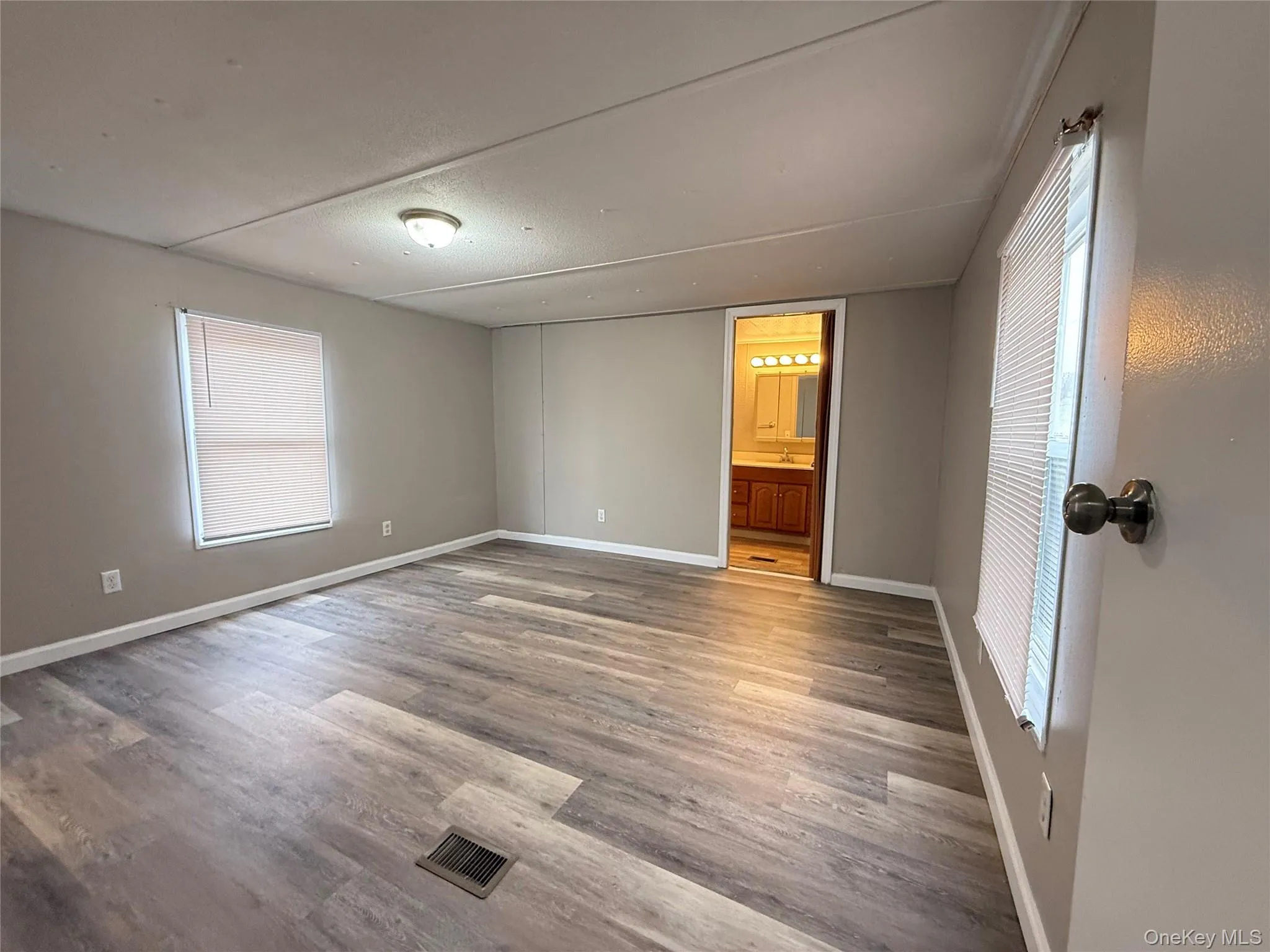 Unfurnished bedroom featuring light wood-style floors, connected bathroom, and a textured ceiling Unfurnished bedroom featuring light wood-style floors, connected bathroom, and a textured ceiling