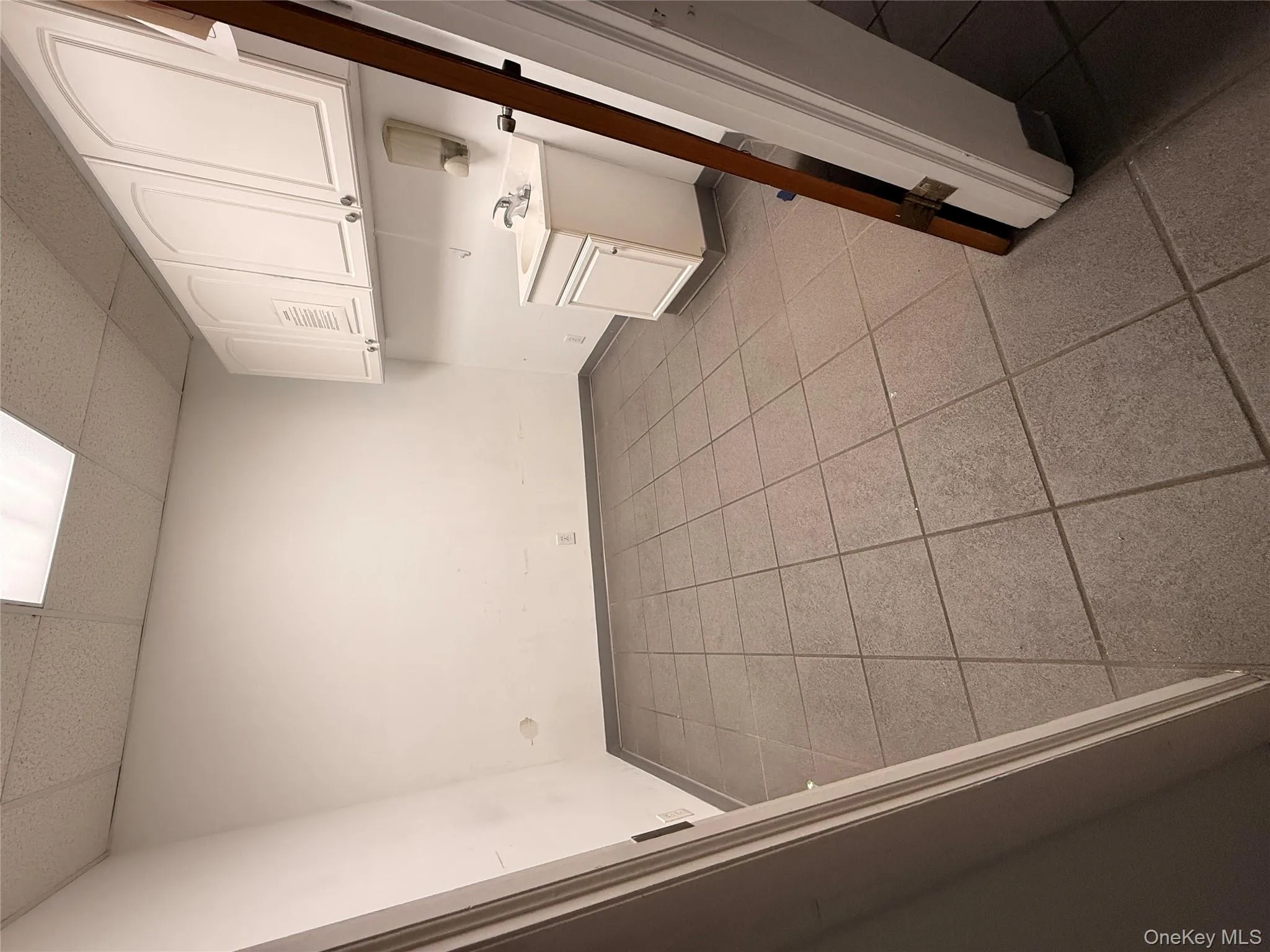 Washroom featuring a drop ceiling and dark tile patterned flooring Washroom featuring a drop ceiling and dark tile patterned flooring