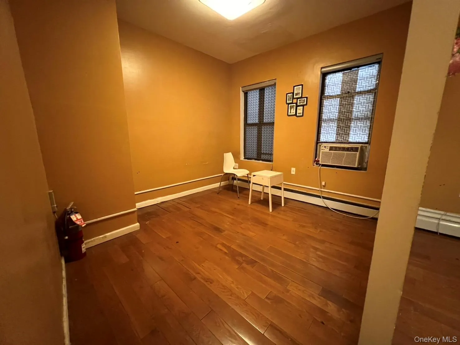 Spare room featuring dark wood-type flooring, cooling unit, and a baseboard radiator Spare room featuring dark wood-type flooring, cooling unit, and a baseboard radiator