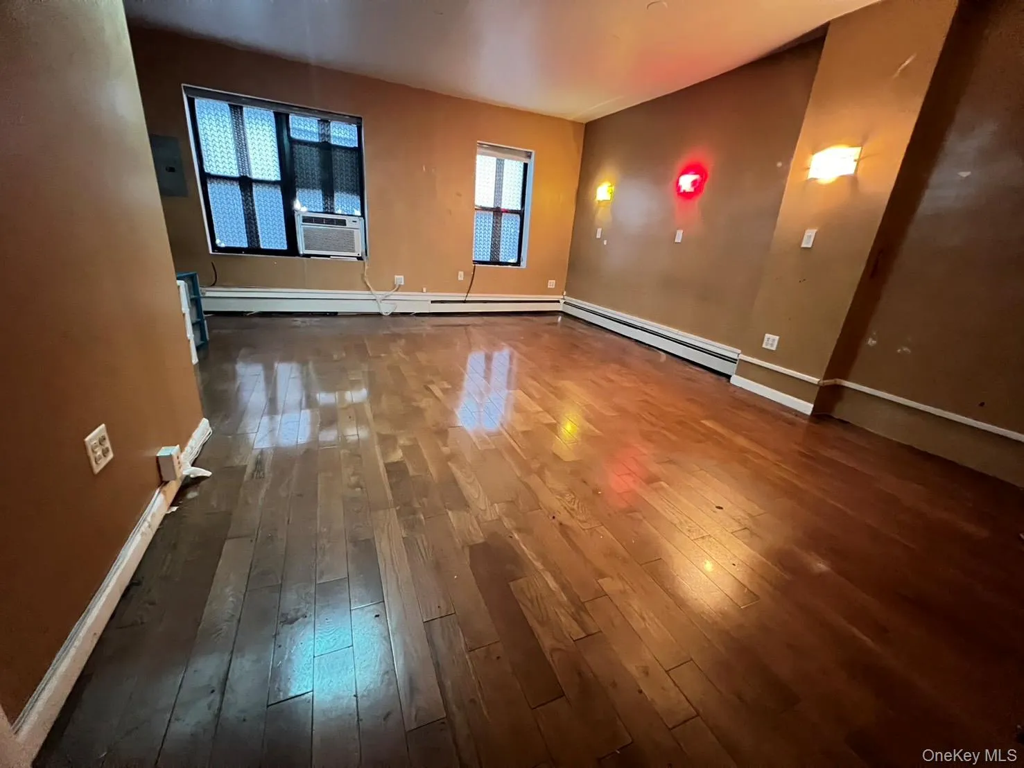 Spare room with dark wood-type flooring, a baseboard heating unit, and cooling unit Spare room with dark wood-type flooring, a baseboard heating unit, and cooling unit