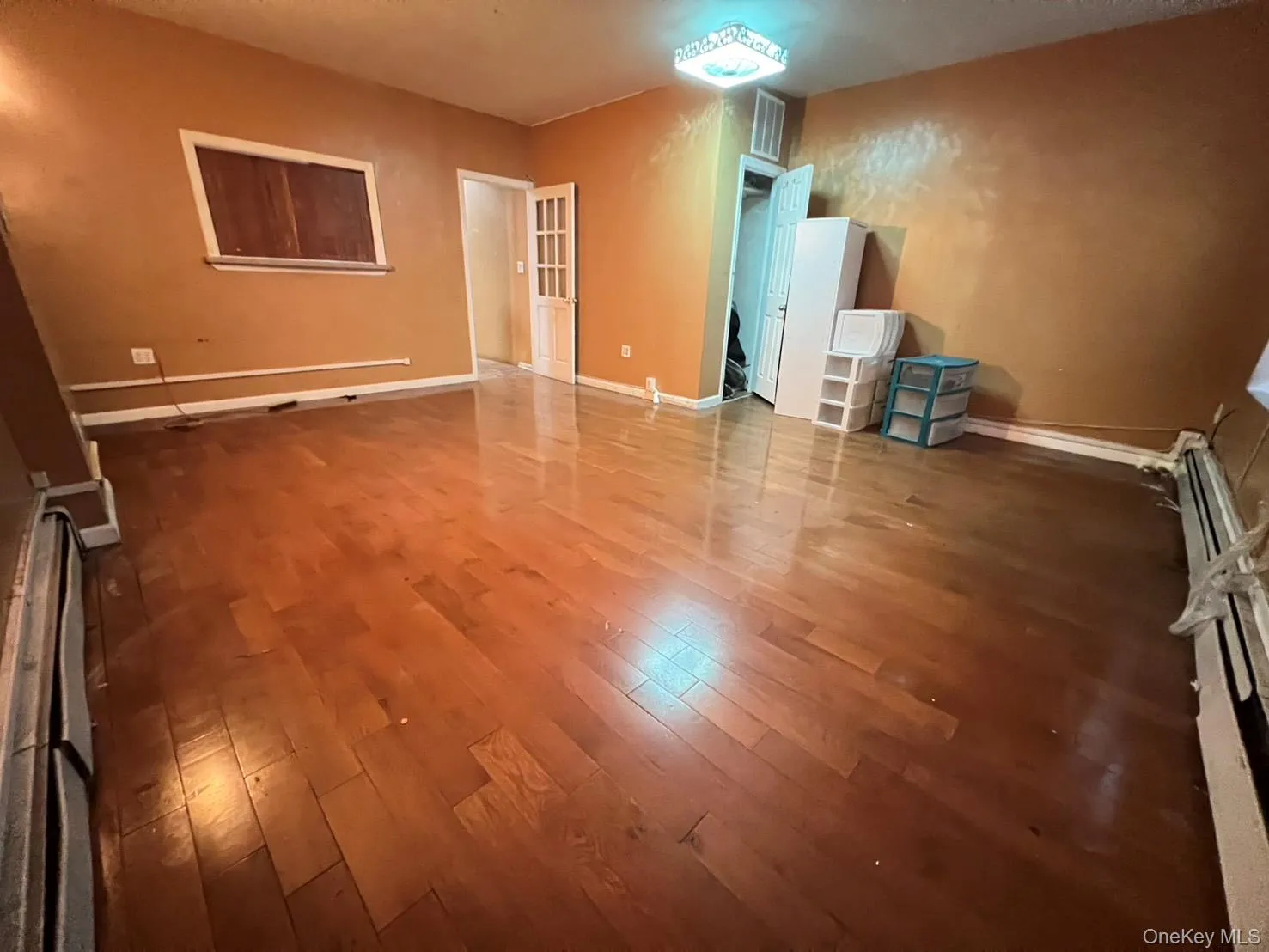 Unfurnished room with wood finished floors, baseboard heating, and a baseboard heating unit Unfurnished room with wood finished floors, baseboard heating, and a baseboard heating unit