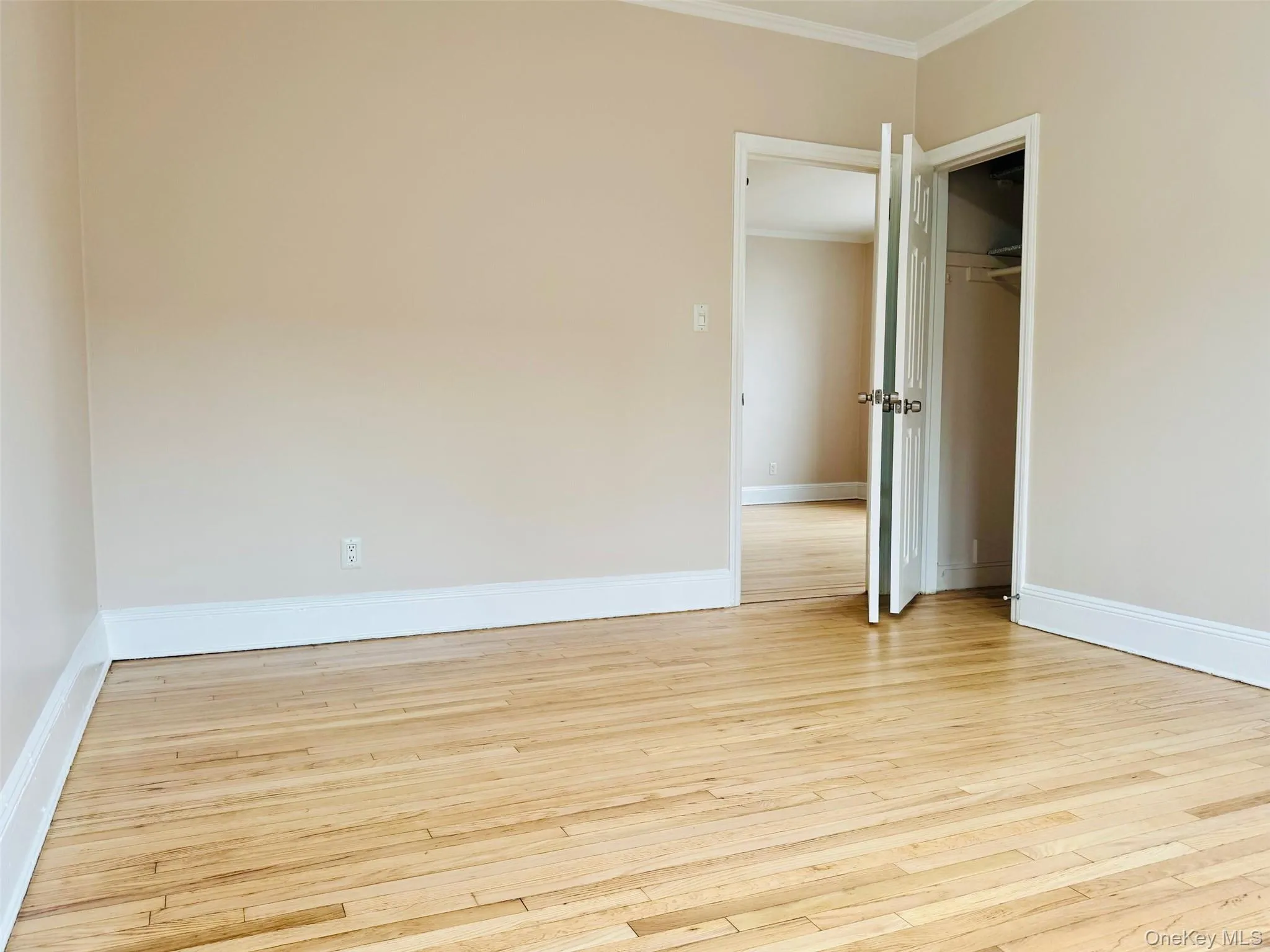 Unfurnished bedroom with light wood-style flooring, ornamental molding, and a closet Unfurnished bedroom with light wood-style flooring, ornamental molding, and a closet
