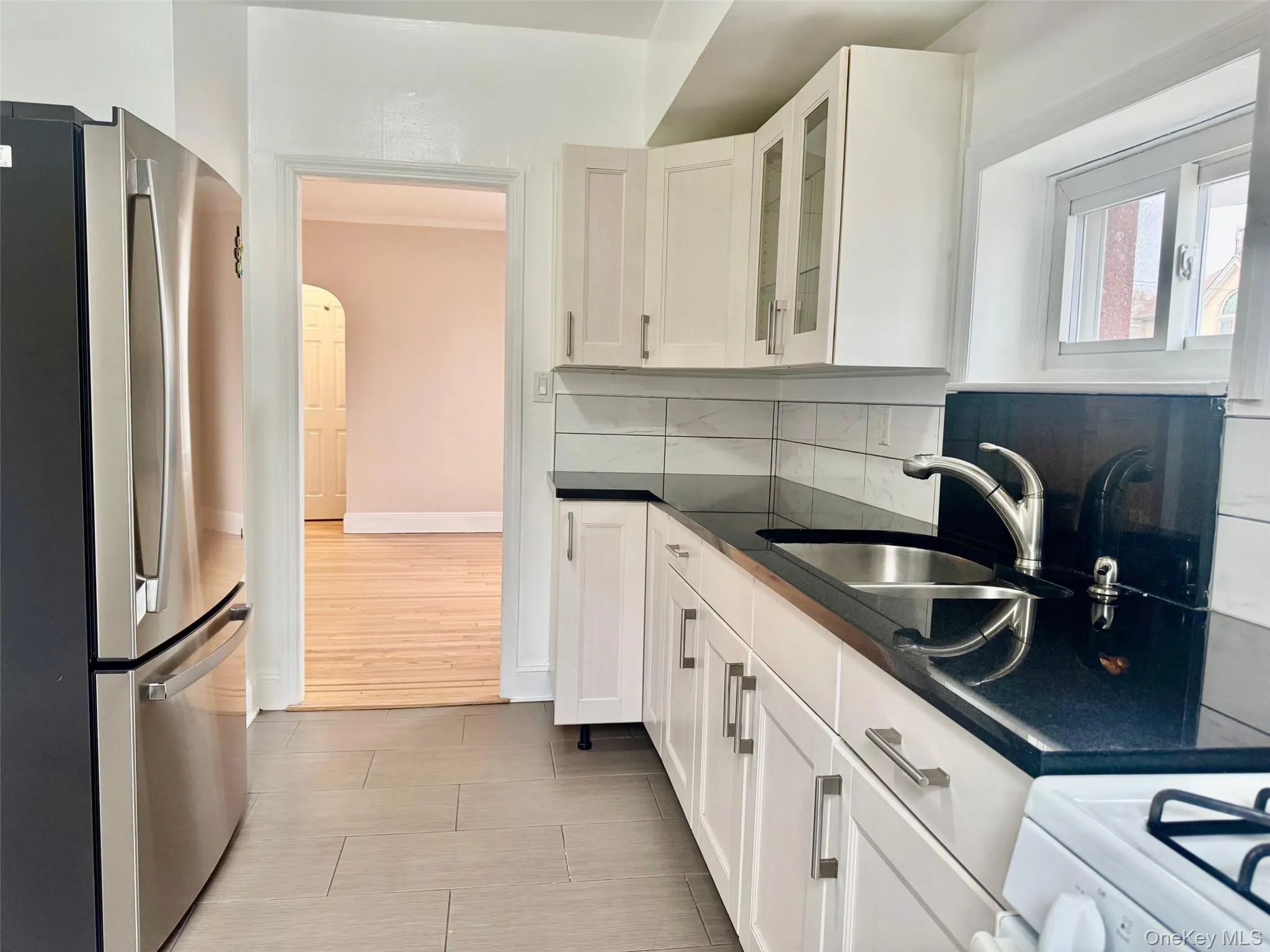 Kitchen with freestanding refrigerator, white cabinets, white range, glass insert cabinets, and tasteful backsplash Kitchen with freestanding refrigerator, white cabinets, white range, glass insert cabinets, and tasteful backsplash