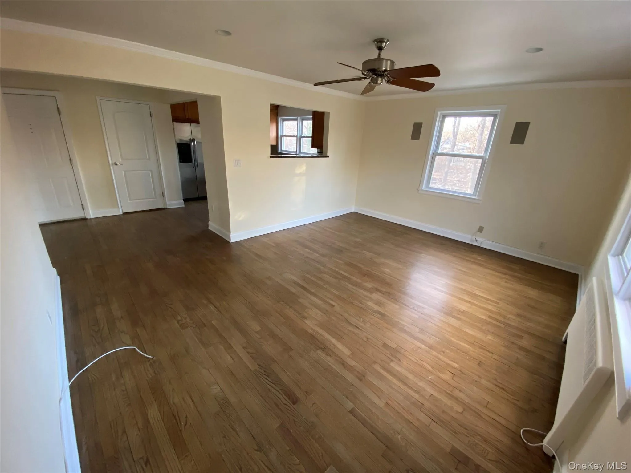 Empty room with healthy amount of natural light, crown molding, and dark wood-style flooring Empty room with healthy amount of natural light, crown molding, and dark wood-style flooring
