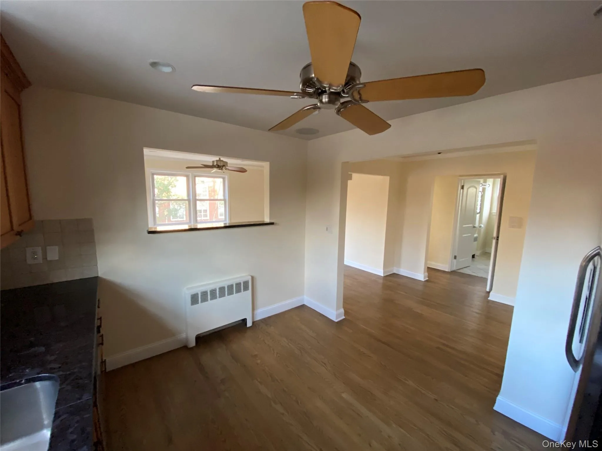 Unfurnished dining area featuring radiator heating unit and dark wood-type flooring Unfurnished dining area featuring radiator heating unit and dark wood-type flooring