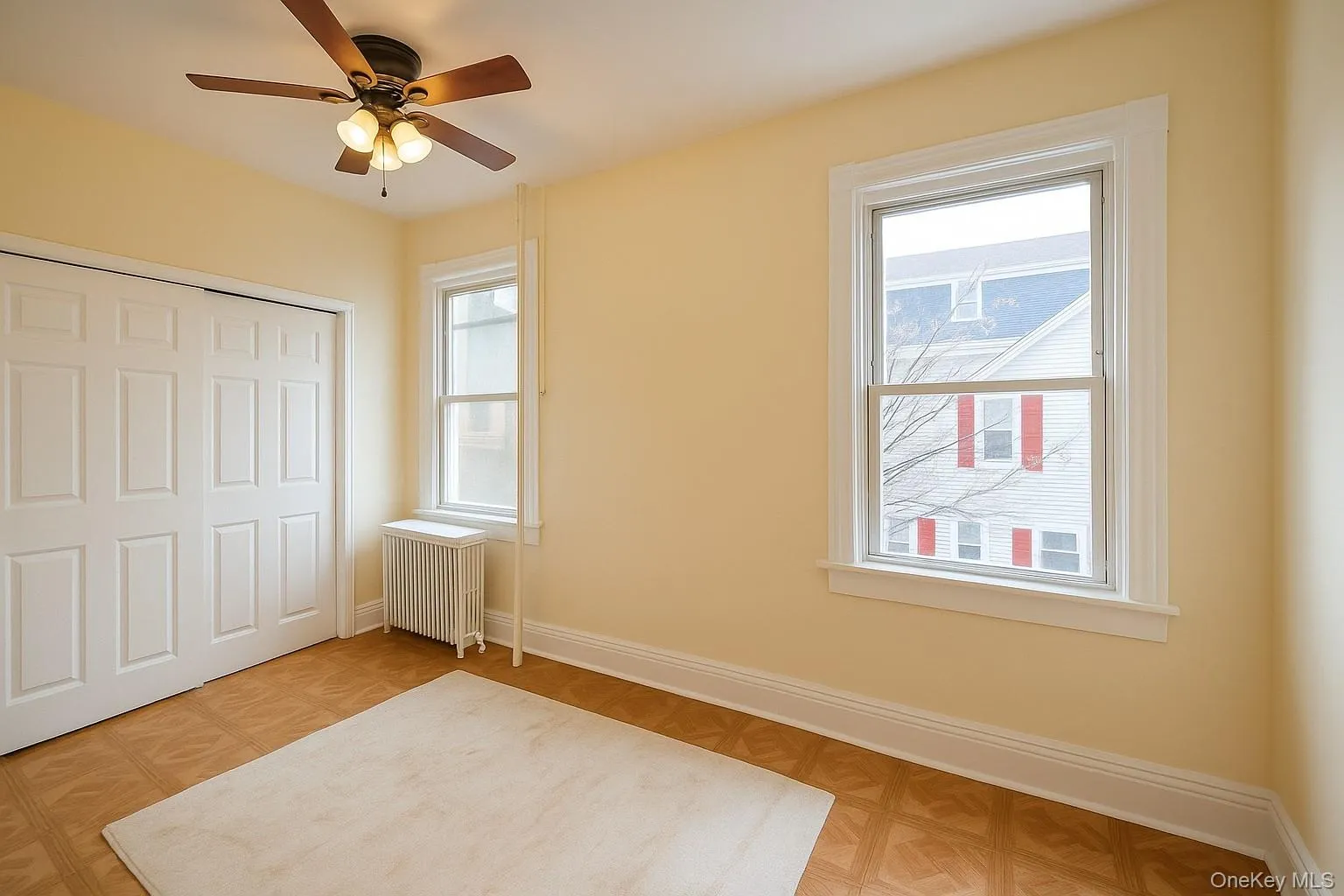 Unfurnished bedroom featuring radiator heating unit, a closet, and a ceiling fan Unfurnished bedroom featuring radiator heating unit, a closet, and a ceiling fan