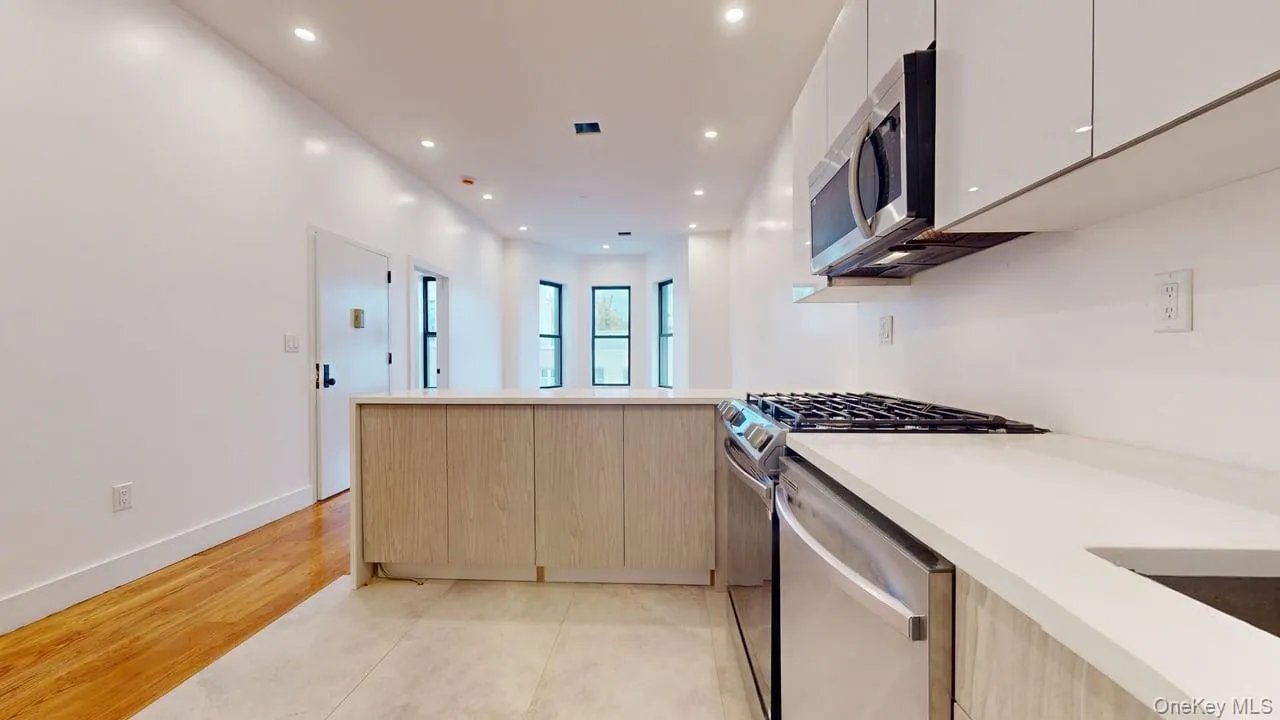 Kitchen featuring modern cabinets, recessed lighting, appliances with stainless steel finishes, a peninsula, and light wood-type flooring Kitchen featuring modern cabinets, recessed lighting, appliances with stainless steel finishes, a peninsula, and light wood-type flooring