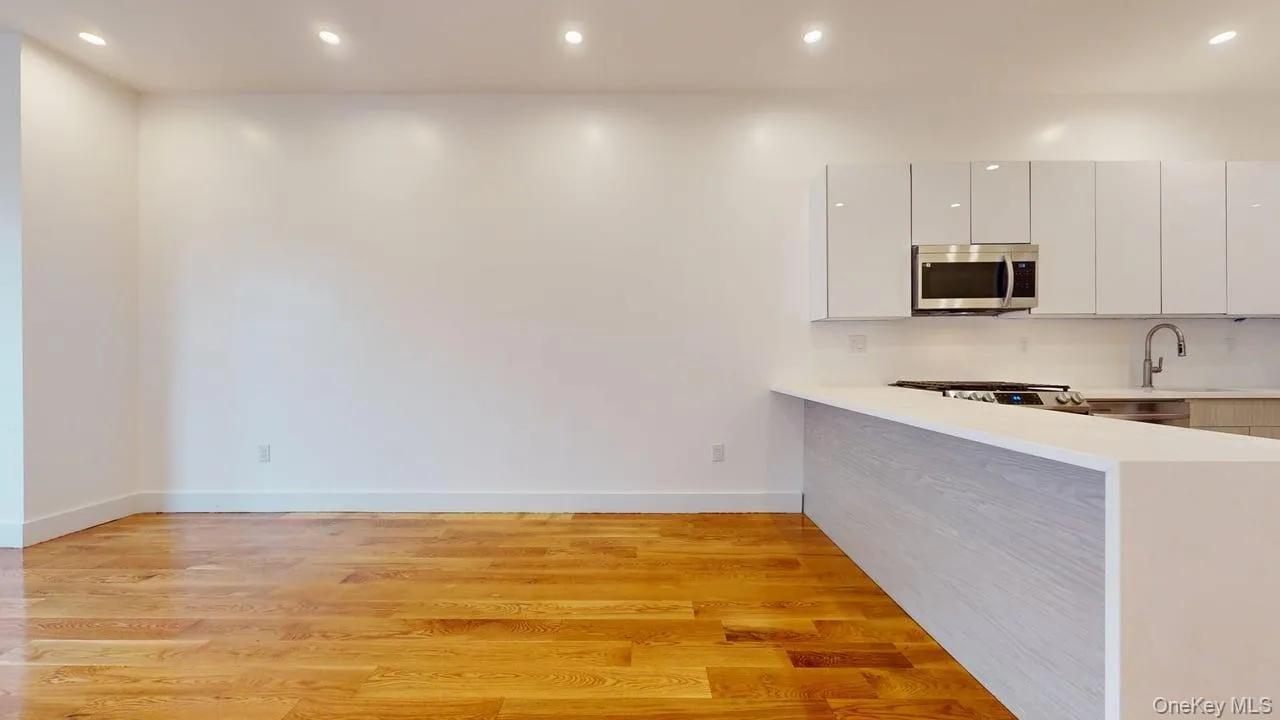 Kitchen featuring recessed lighting, modern cabinets, light wood-type flooring, a peninsula, and stainless steel microwave Kitchen featuring recessed lighting, modern cabinets, light wood-type flooring, a peninsula, and stainless steel microwave