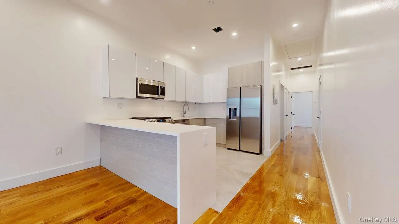 Kitchen with light wood finished floors, stainless steel appliances, a peninsula, modern cabinets, and recessed lighting Kitchen with light wood finished floors, stainless steel appliances, a peninsula, modern cabinets, and recessed lighting