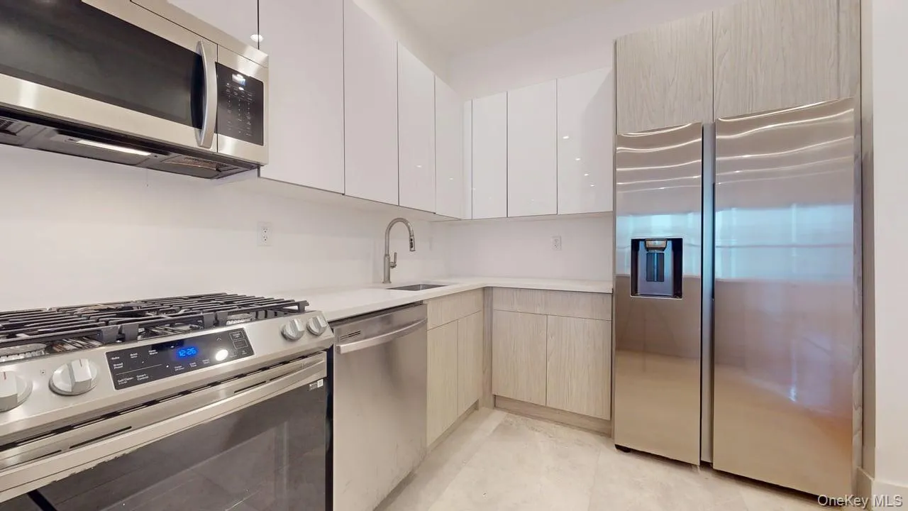 Kitchen featuring appliances with stainless steel finishes, modern cabinets, white cabinetry, and light tile patterned floors Kitchen featuring appliances with stainless steel finishes, modern cabinets, white cabinetry, and light tile patterned floors