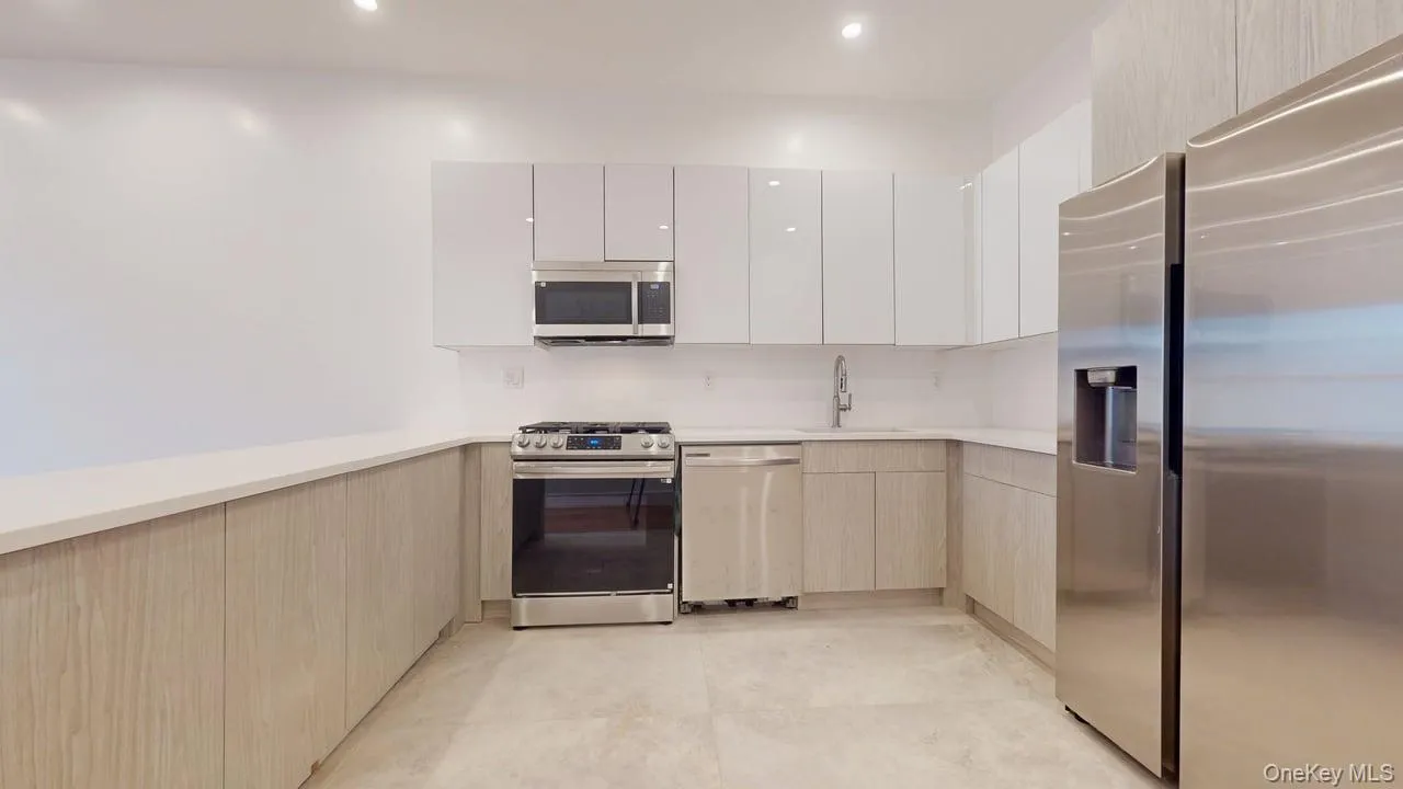 Kitchen with stainless steel appliances, modern cabinets, a peninsula, recessed lighting, and white cabinetry Kitchen with stainless steel appliances, modern cabinets, a peninsula, recessed lighting, and white cabinetry