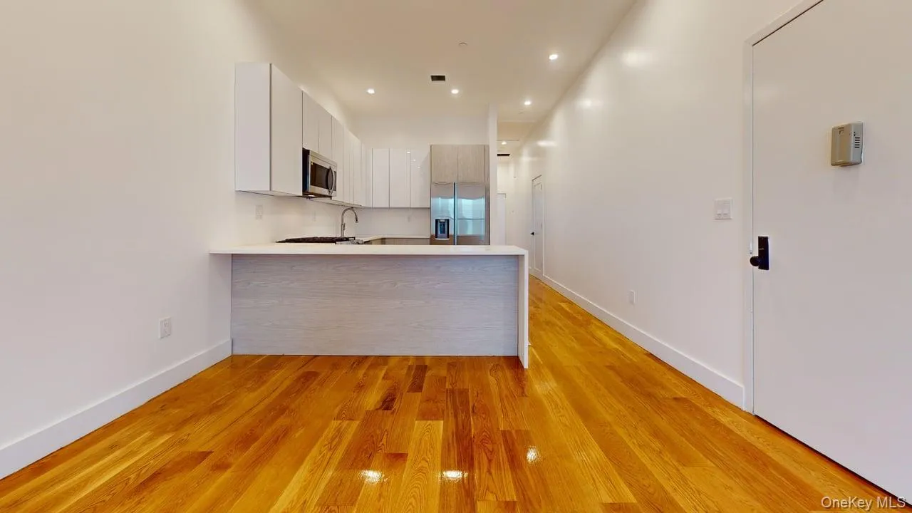 Kitchen featuring a peninsula, stainless steel appliances, recessed lighting, light wood finished floors, and a kitchen bar Kitchen featuring a peninsula, stainless steel appliances, recessed lighting, light wood finished floors, and a kitchen bar