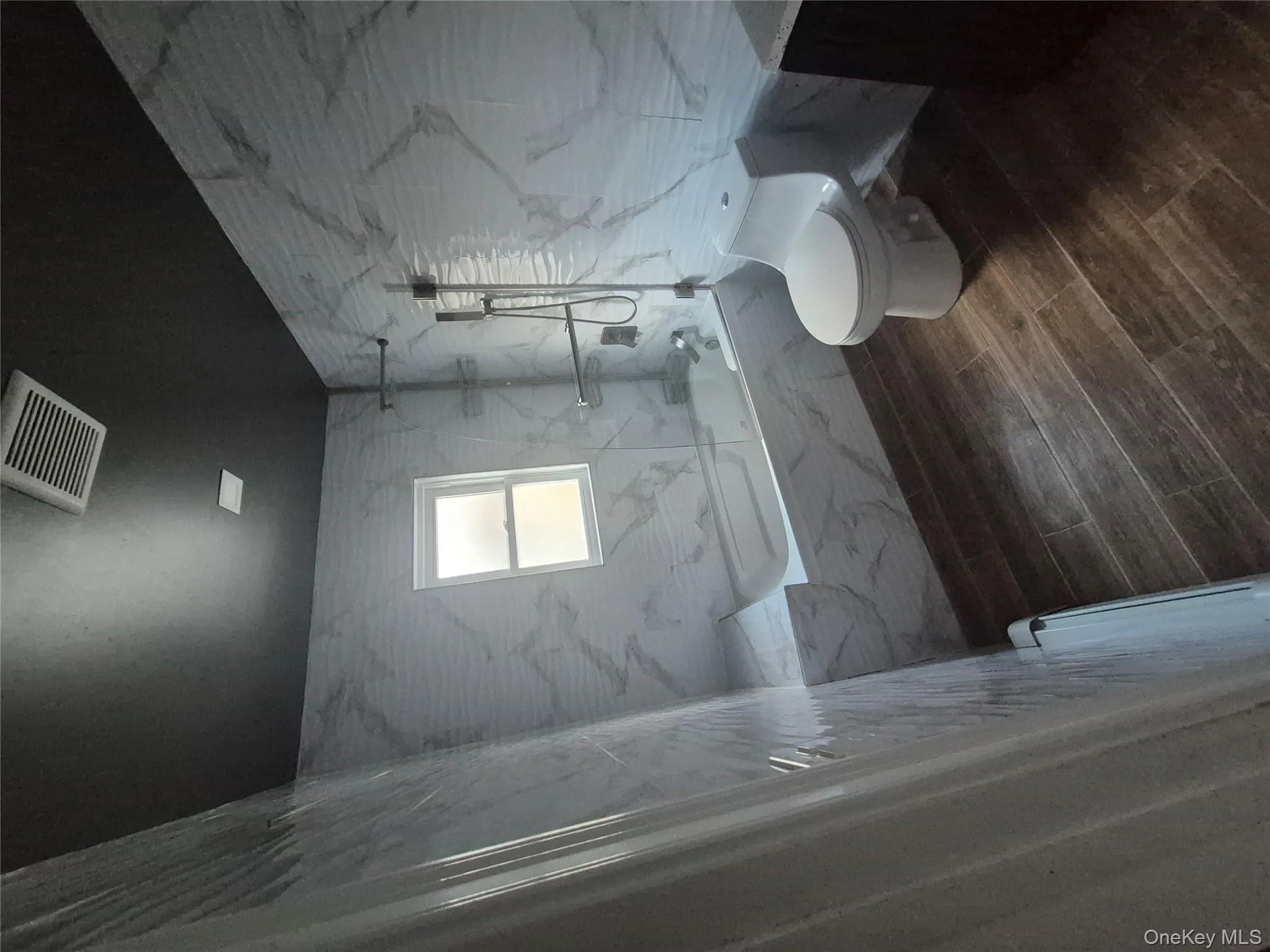 Full bath with tile walls, a combined bath / shower with marble appearance, dark wood-style floors, and vanity Full bath with tile walls, a combined bath / shower with marble appearance, dark wood-style floors, and vanity