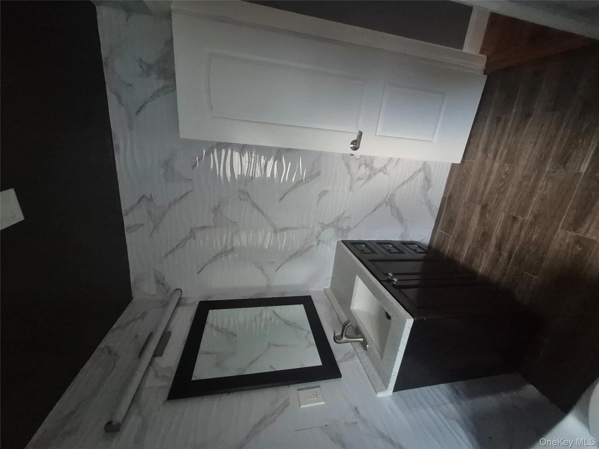 Bathroom with vanity, dark wood finished floors, and tile walls Bathroom with vanity, dark wood finished floors, and tile walls