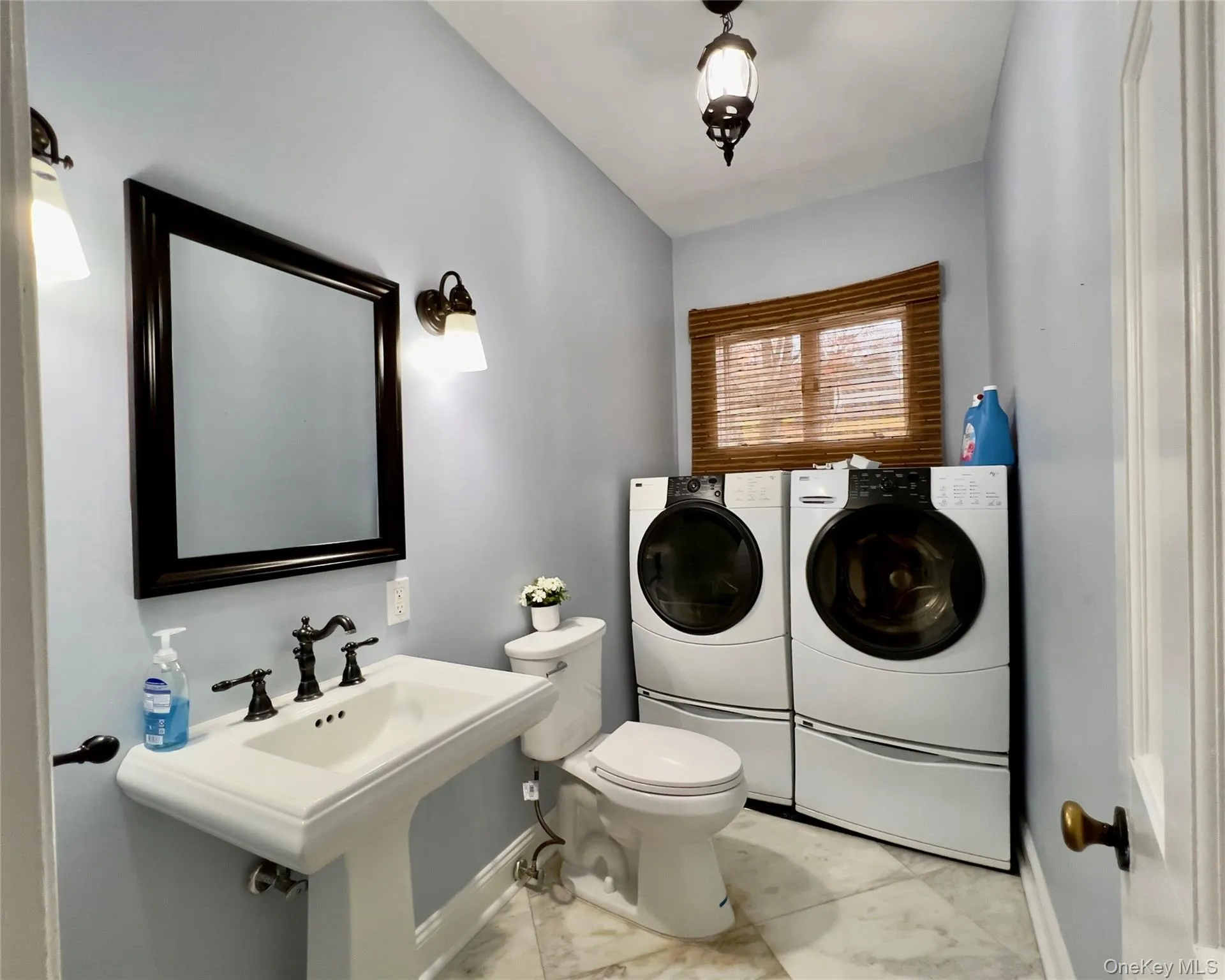 Half bathroom featuring washing machine and clothes dryer and light tile floors Half bathroom featuring washing machine and clothes dryer and light tile floors