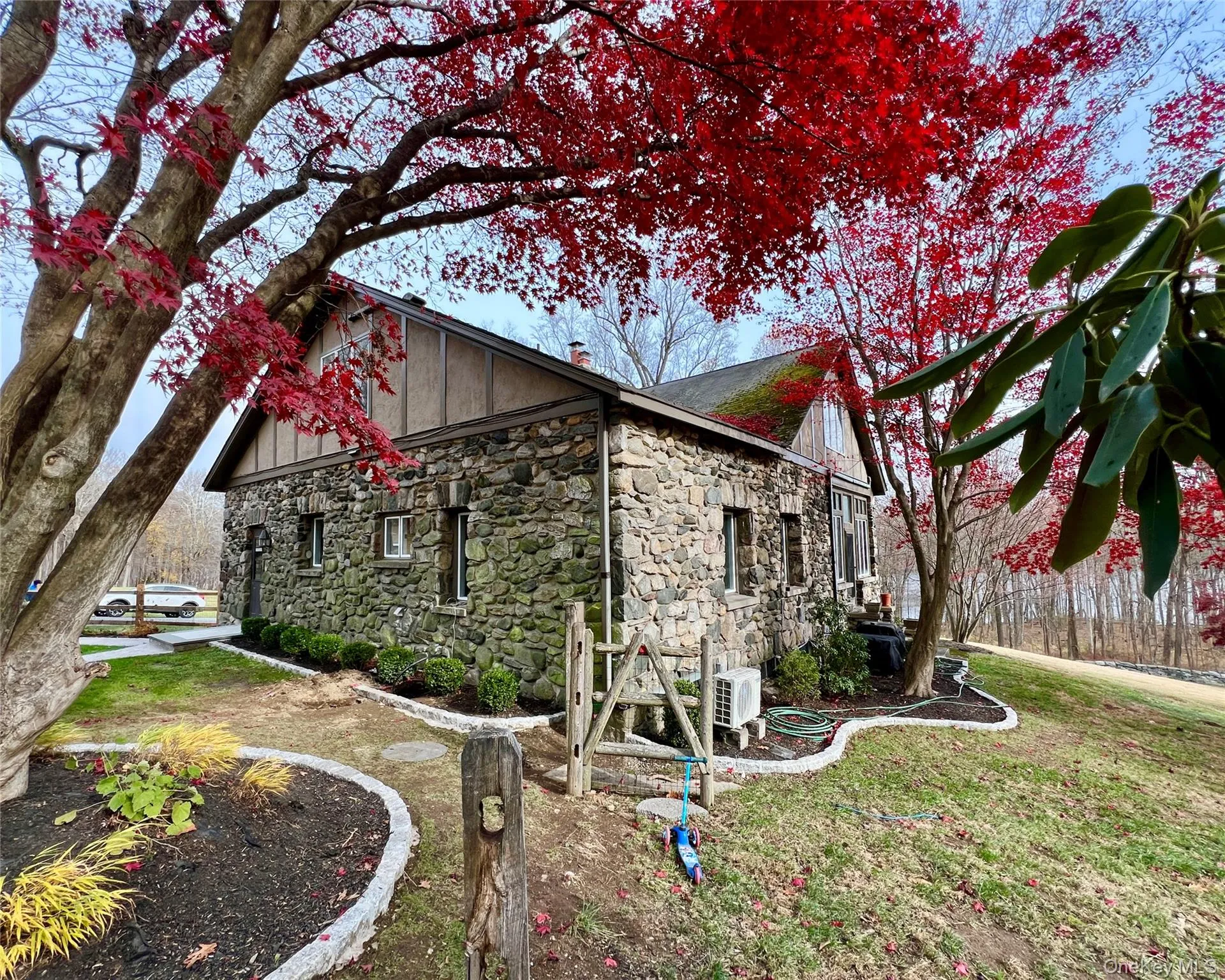 View of side of property featuring beautiful masonry stone and manicured landscaping View of side of property featuring beautiful masonry stone and manicured landscaping