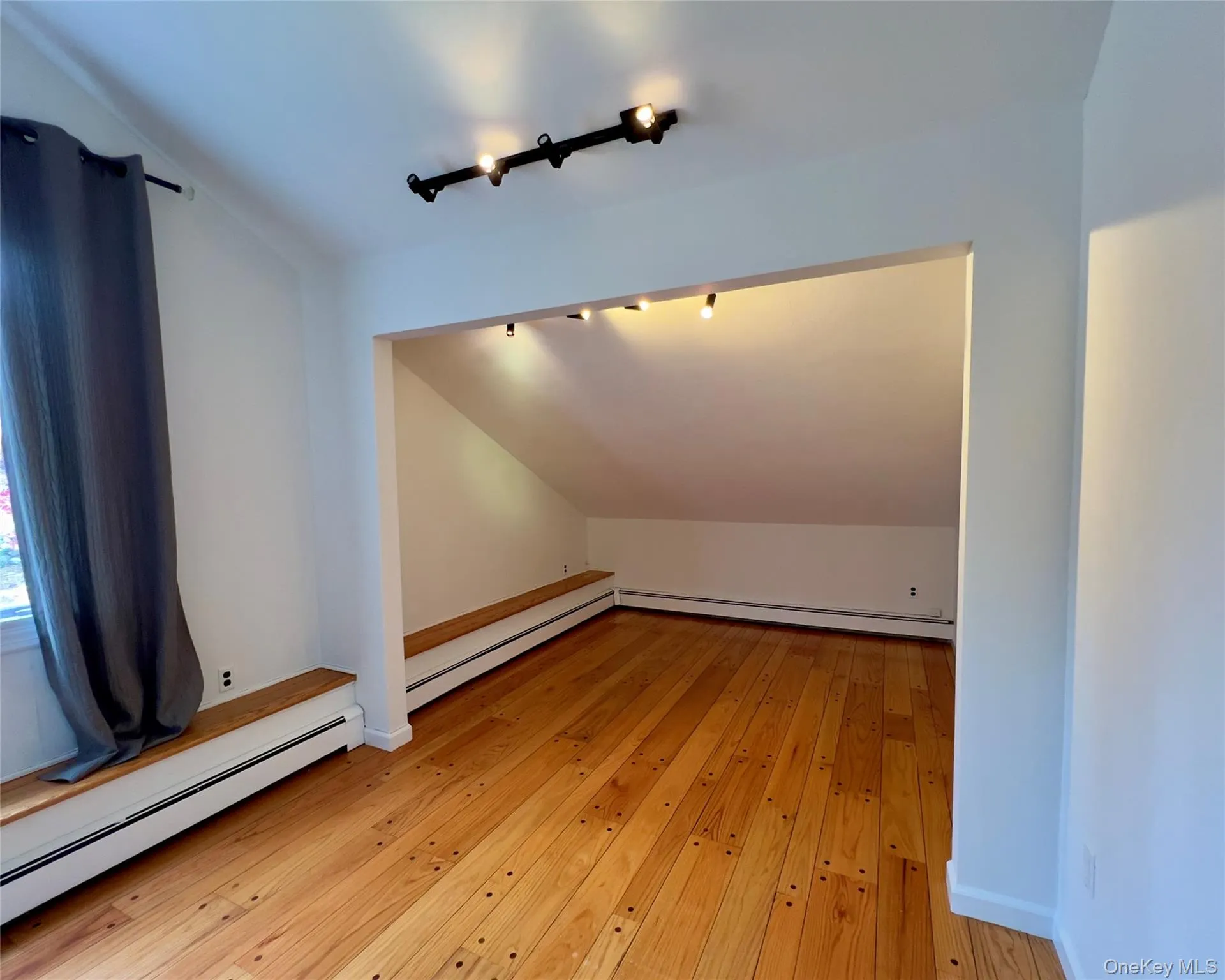 Bedroom #3, with lofted ceilings, baseboard heating, hardwood floors, a wall mounted AC, a closet, and track lighting Bedroom #3, with lofted ceilings, baseboard heating, hardwood floors, a wall mounted AC, a closet, and track lighting