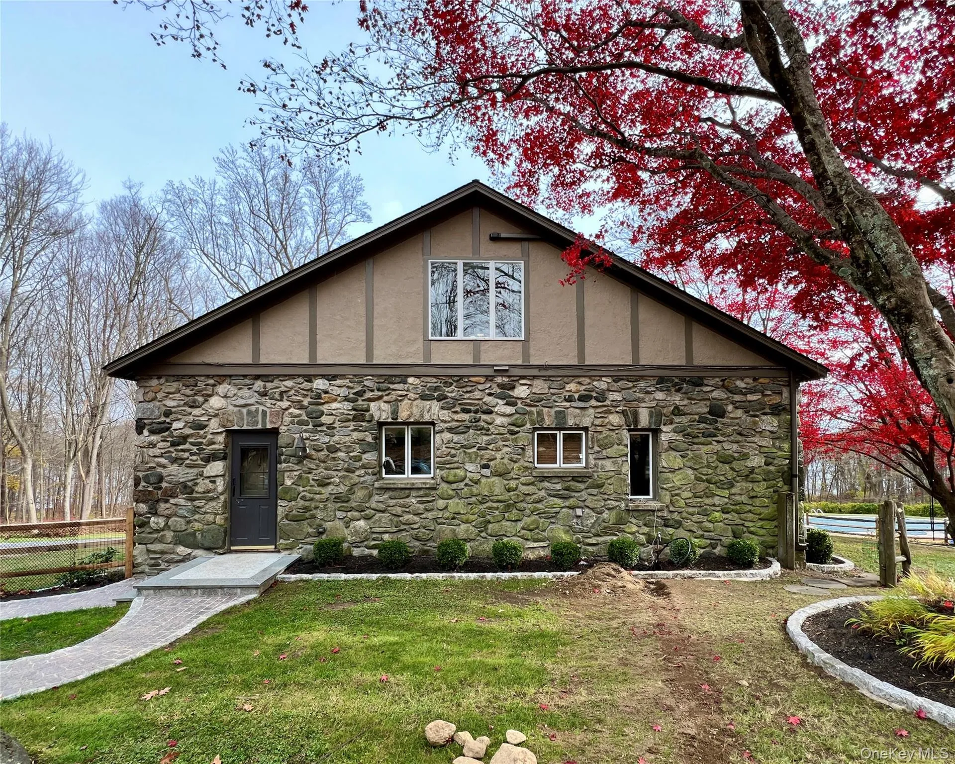 View of side of property featuring beautiful masonry stone and manicured landscaping View of side of property featuring beautiful masonry stone and manicured landscaping