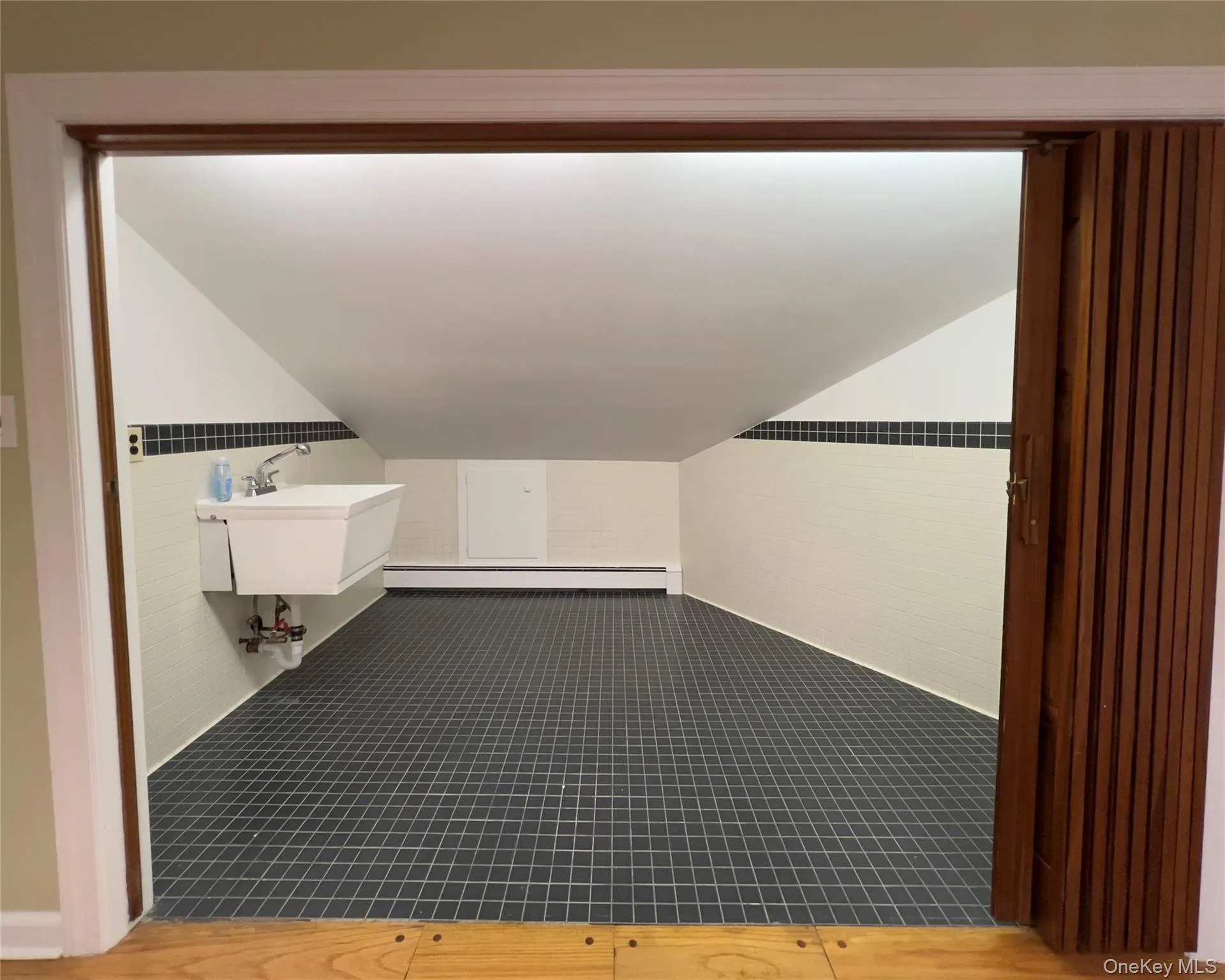 Bonus room with tile floors, baseboard heating, a wainscoted wall, and slanted ceiling Bonus room with tile floors, baseboard heating, a wainscoted wall, and slanted ceiling