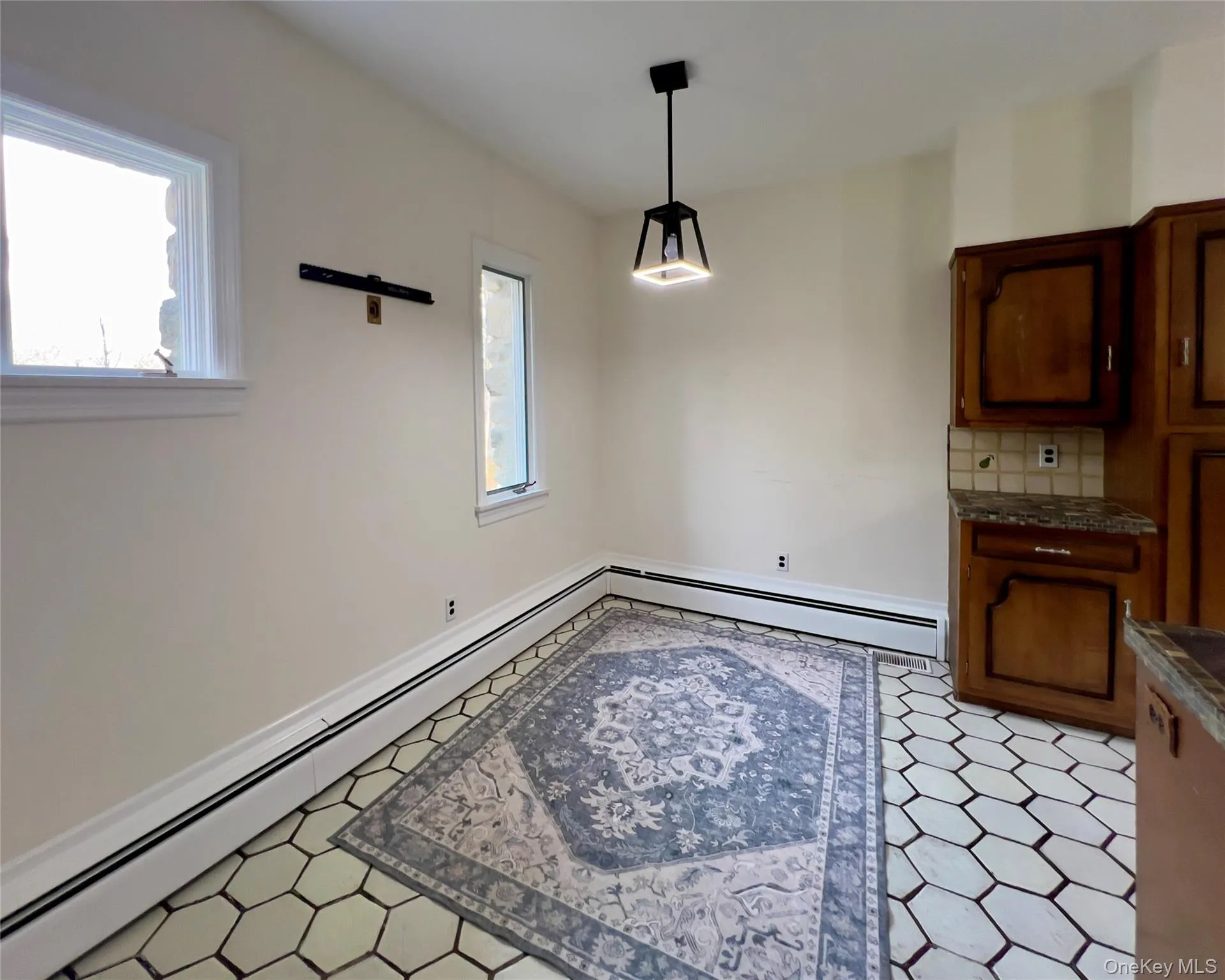 Kitchen with open shelves, stainless steel appliances, a peninsula, decorative backsplash, stone tile countertops, brown cabinetry and baseboard heating Kitchen with open shelves, stainless steel appliances, a peninsula, decorative backsplash, stone tile countertops, brown cabinetry and baseboard heating