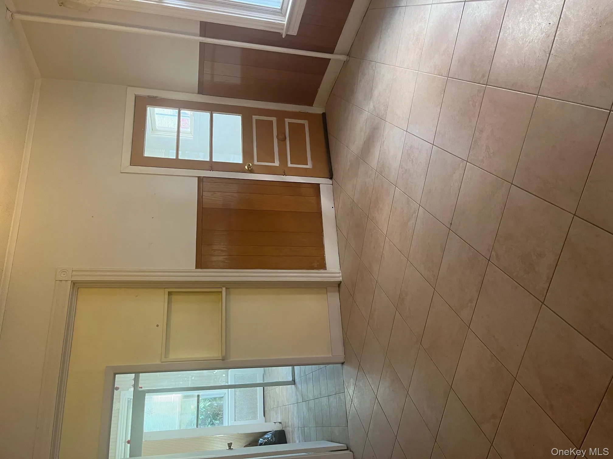 Empty room featuring wood walls, crown molding, light tile patterned floors, and wainscoting Empty room featuring wood walls, crown molding, light tile patterned floors, and wainscoting