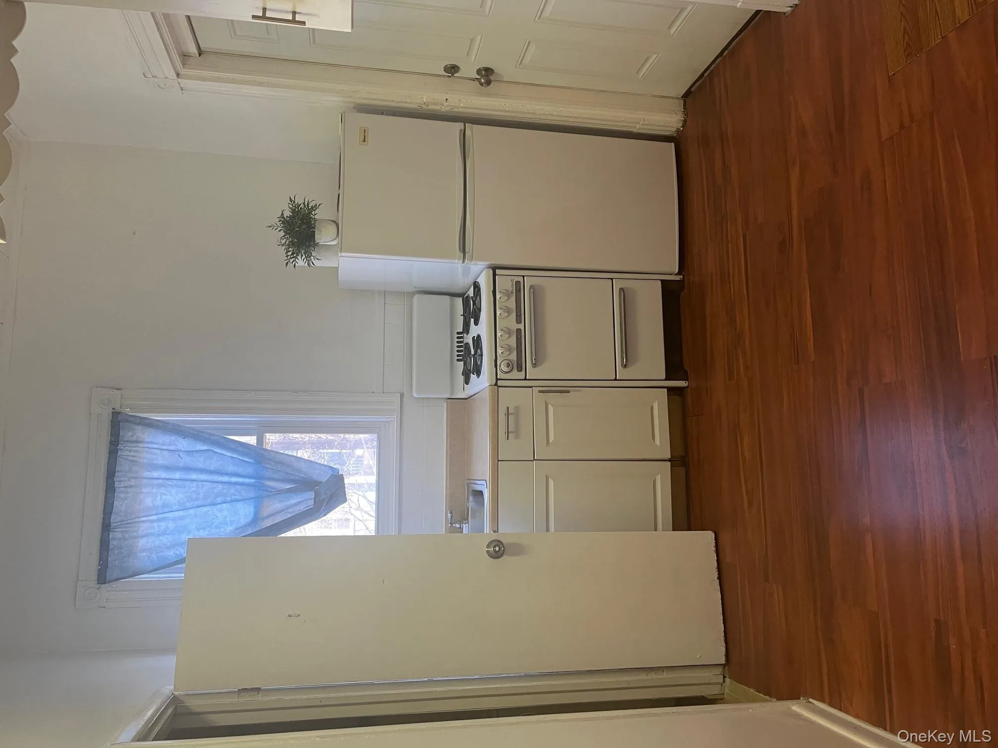 Kitchen with white cabinetry, white range with gas stovetop, fridge, light countertops, and dark wood finished floors Kitchen with white cabinetry, white range with gas stovetop, fridge, light countertops, and dark wood finished floors