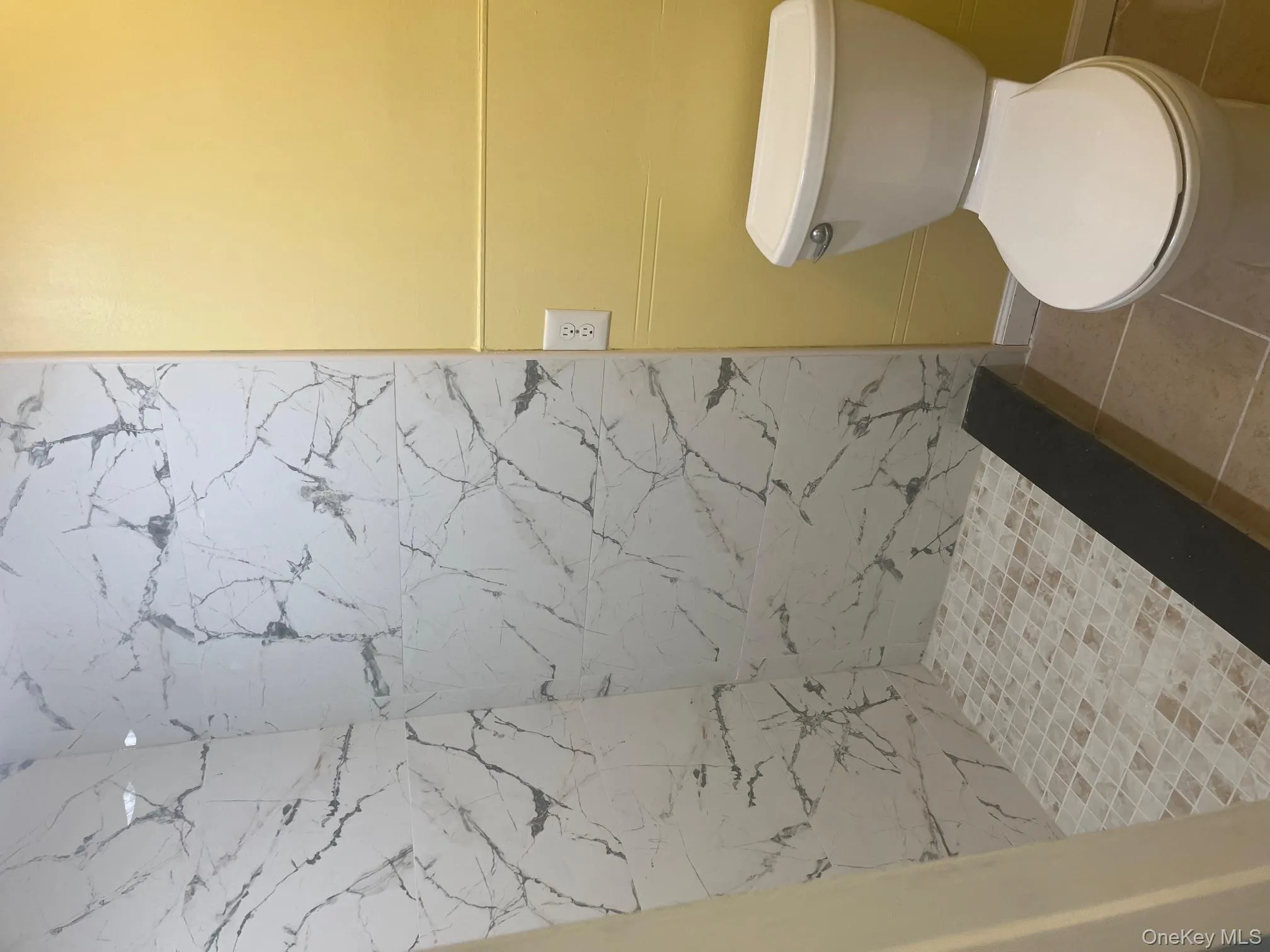 Bathroom featuring a marble finish shower and light tile patterned floors Bathroom featuring a marble finish shower and light tile patterned floors