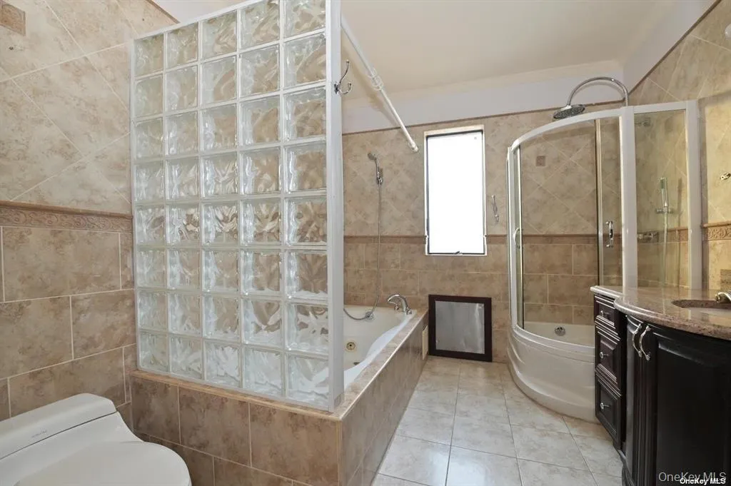 Bathroom with vanity, tile walls, light tile patterned flooring, tiled shower / bath, and ornamental molding Bathroom with vanity, tile walls, light tile patterned flooring, tiled shower / bath, and ornamental molding