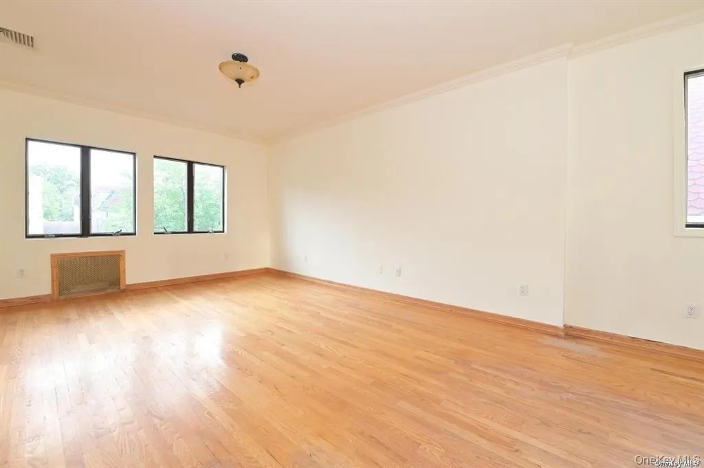 Empty room featuring light wood-style flooring, ornamental molding, and plenty of natural light Empty room featuring light wood-style flooring, ornamental molding, and plenty of natural light