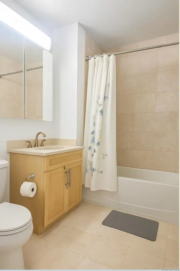 Full bath with shower / bath combo with shower curtain, vanity, and light tile patterned flooring Full bath with shower / bath combo with shower curtain, vanity, and light tile patterned flooring