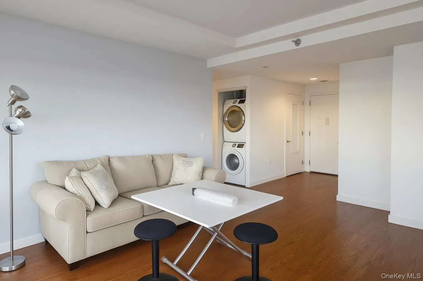 Living area with dark wood finished floors and stacked washing machine and dryer Living area with dark wood finished floors and stacked washing machine and dryer