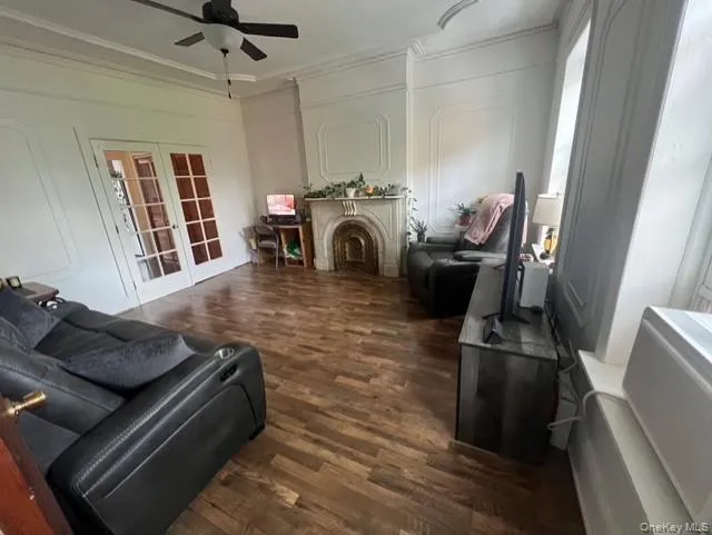 Living area with a decorative wall, dark wood-type flooring, a fireplace, french doors, and ornamental molding Living area with a decorative wall, dark wood-type flooring, a fireplace, french doors, and ornamental molding