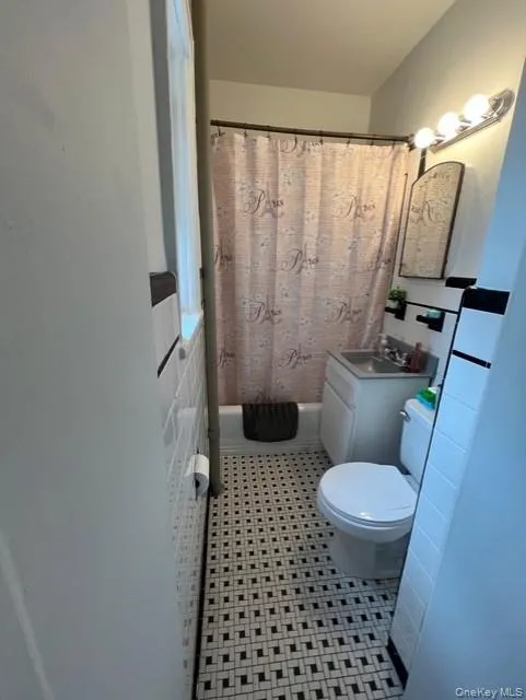 Full bathroom featuring vanity, light tile patterned flooring, and shower / tub combo with curtain Full bathroom featuring vanity, light tile patterned flooring, and shower / tub combo with curtain