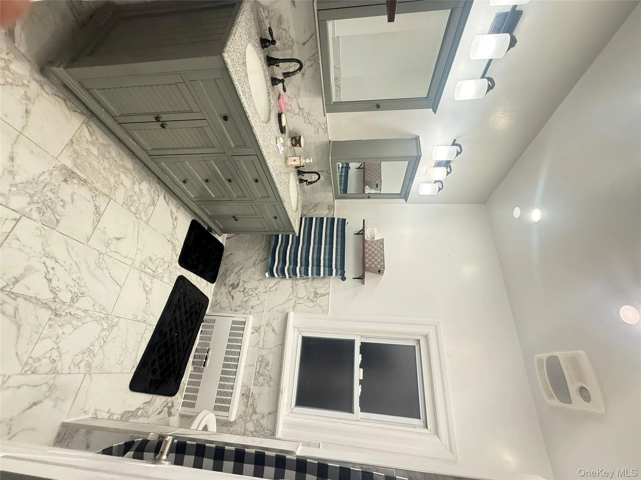 Full bath with tile walls, light marble finish flooring, double vanity, radiator, and a wainscoted wall Full bath with tile walls, light marble finish flooring, double vanity, radiator, and a wainscoted wall