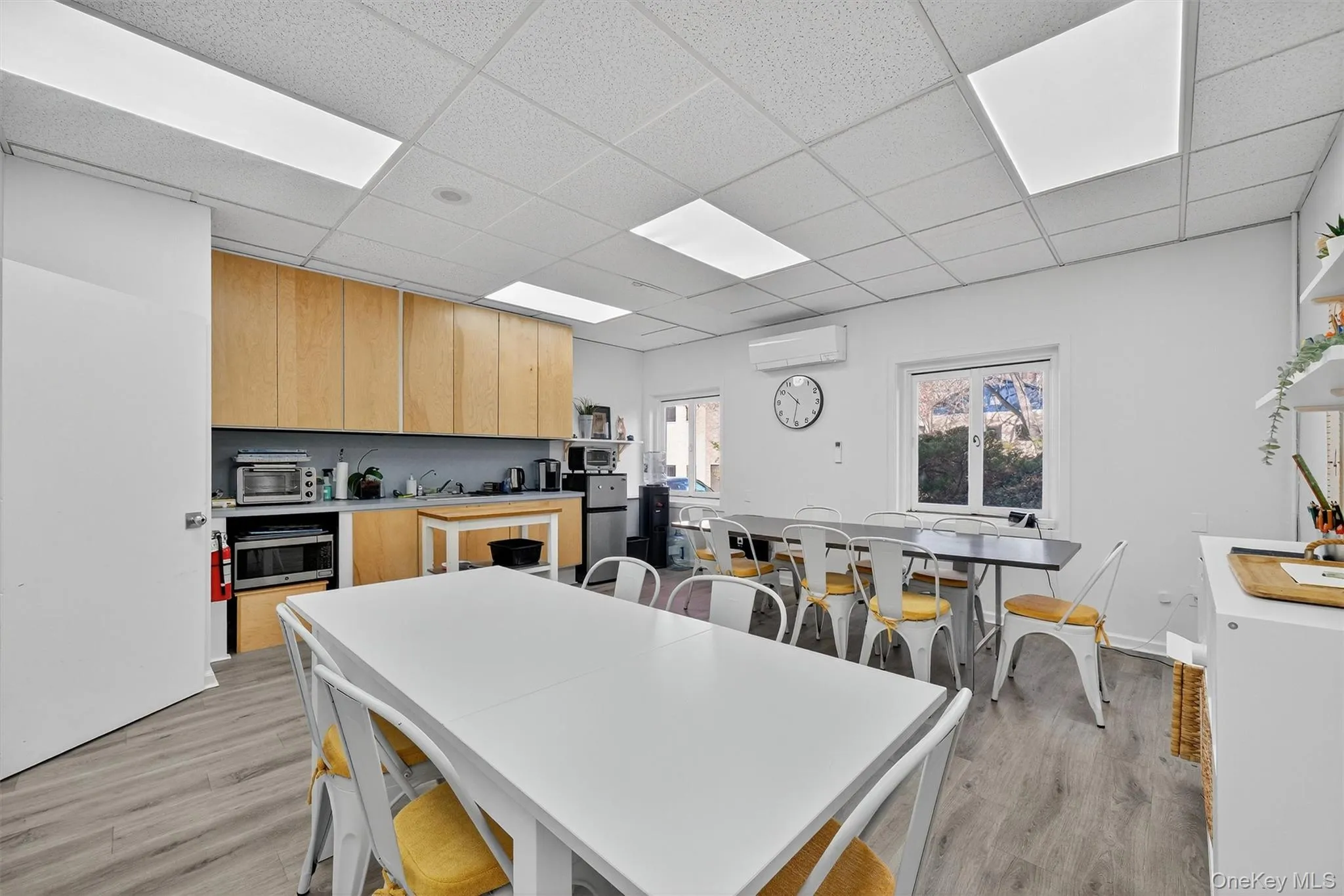 Kitchen with a paneled ceiling, light wood finished floors, light countertops, light brown cabinets, and appliances with stainless steel finishes Kitchen with a paneled ceiling, light wood finished floors, light countertops, light brown cabinets, and appliances with stainless steel finishes