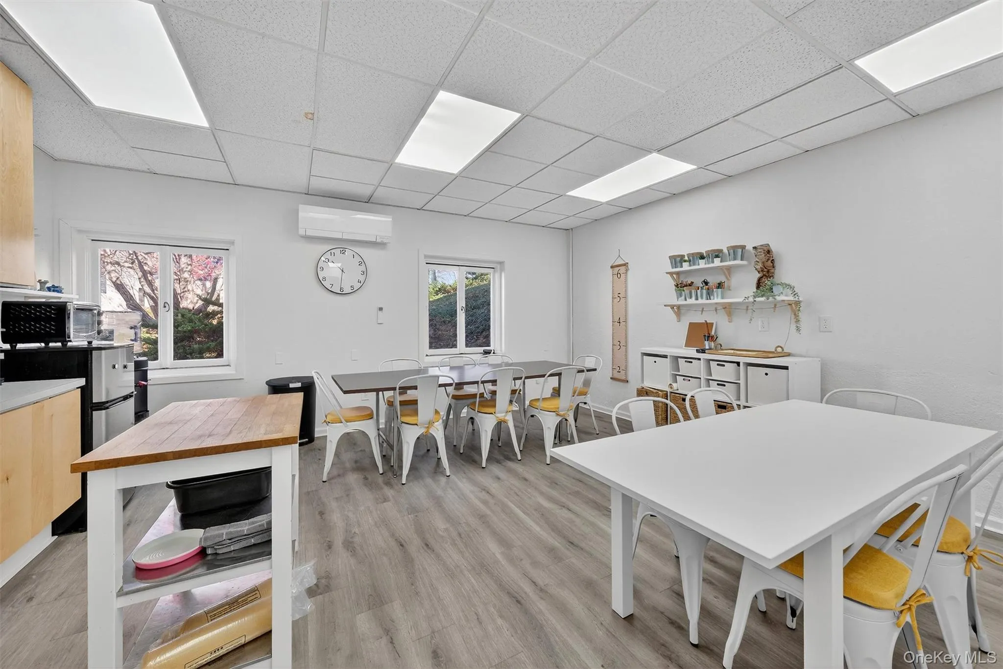 Dining room featuring a drop ceiling, light wood-style floors, and an AC wall unit Dining room featuring a drop ceiling, light wood-style floors, and an AC wall unit