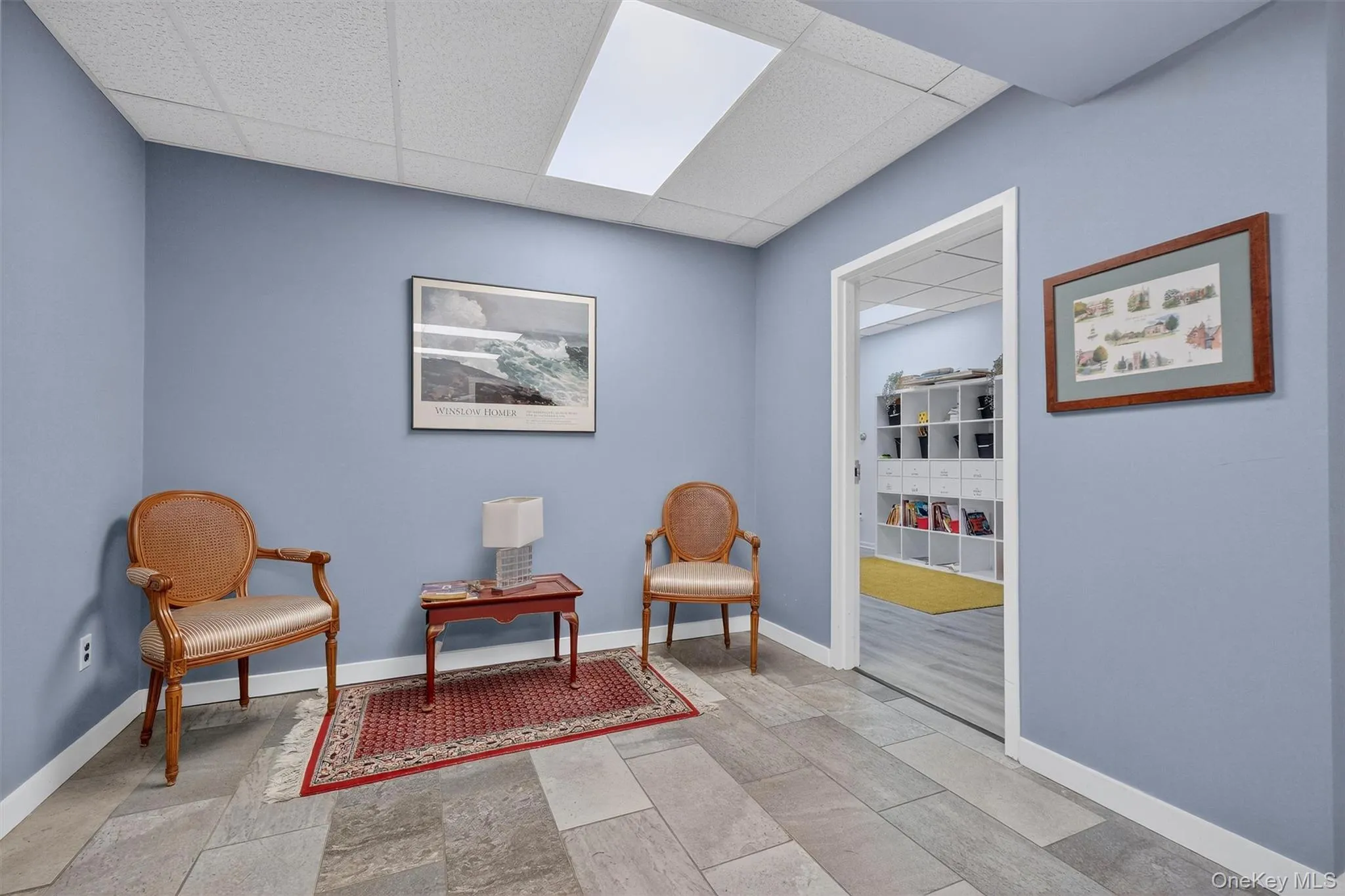 Living area featuring a paneled ceiling and baseboards Living area featuring a paneled ceiling and baseboards