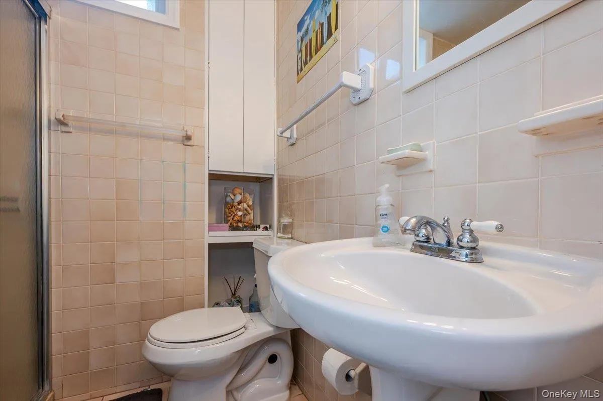 Full bathroom with tile walls, a shower with shower door, and decorative backsplash Full bathroom with tile walls, a shower with shower door, and decorative backsplash
