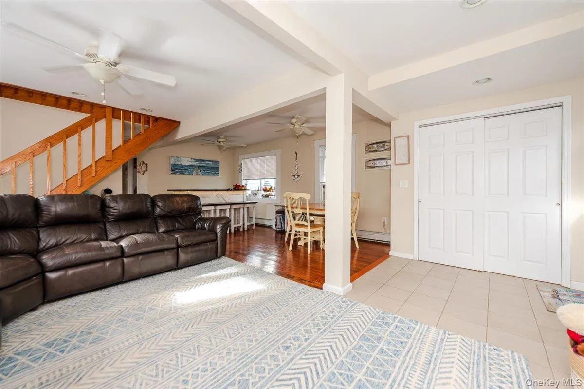 Living area featuring light tile patterned floors, a baseboard heating unit, and beam ceiling Living area featuring light tile patterned floors, a baseboard heating unit, and beam ceiling