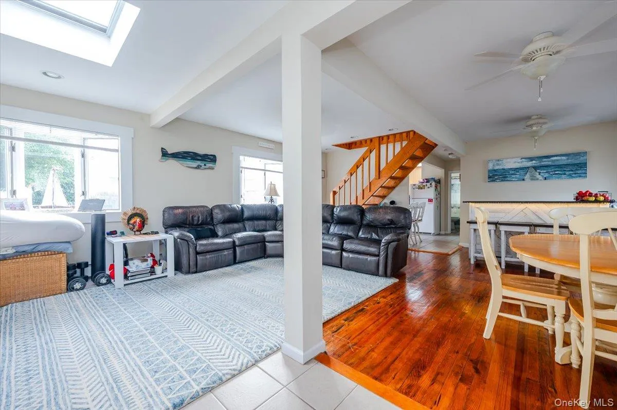 Living area featuring beamed ceiling, healthy amount of natural light, a ceiling fan, a skylight, and light tile patterned flooring Living area featuring beamed ceiling, healthy amount of natural light, a ceiling fan, a skylight, and light tile patterned flooring