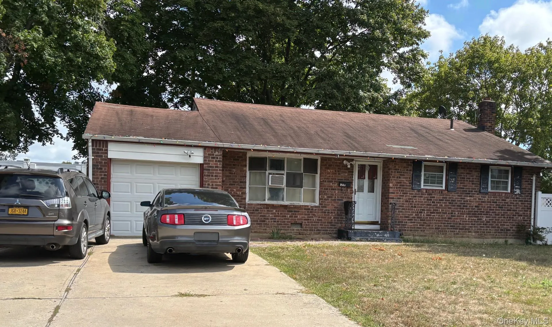 Ranch-style home with a garage, brick siding, a front lawn, concrete driveway, and a chimney Ranch-style home with a garage, brick siding, a front lawn, concrete driveway, and a chimney
