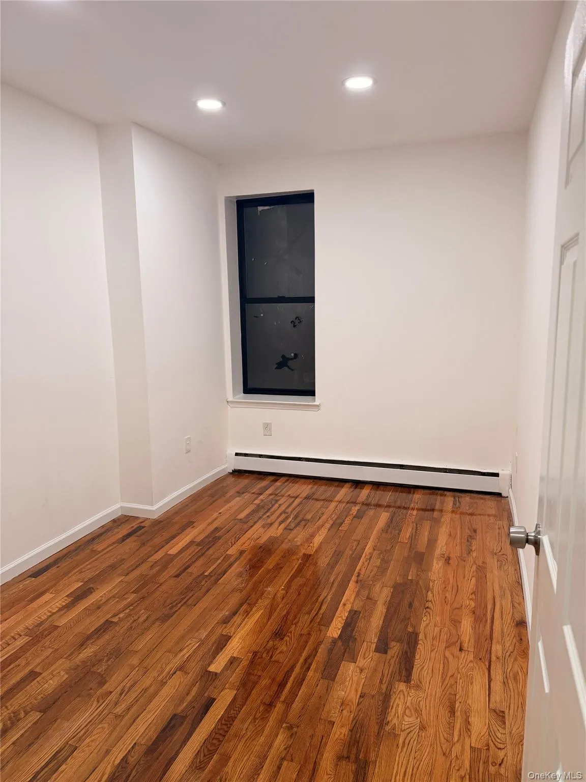 Empty room featuring wood finished floors, baseboard heating, and recessed lighting Empty room featuring wood finished floors, baseboard heating, and recessed lighting