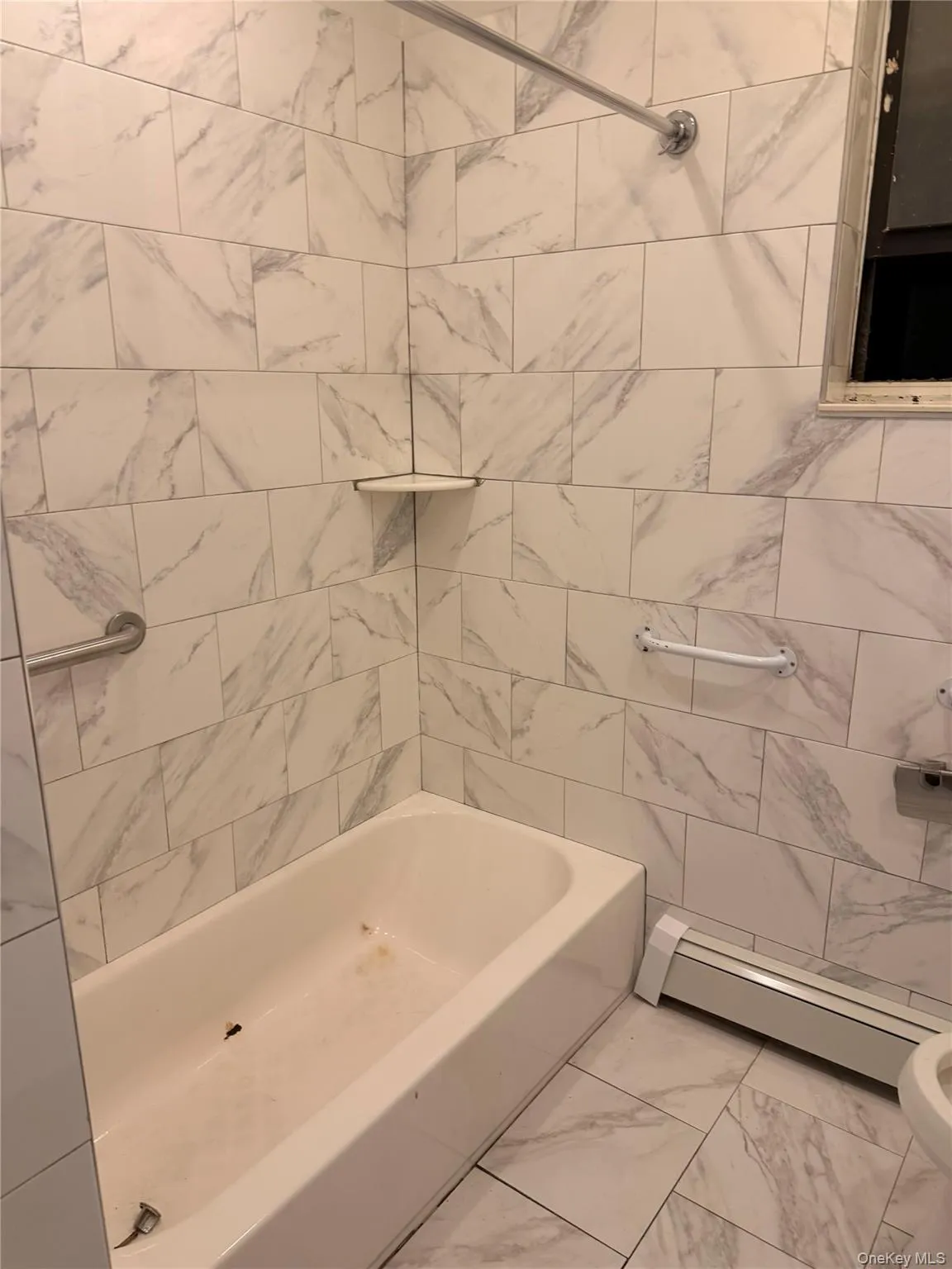 Bathroom with marble look tile flooring, a baseboard radiator, and shower / washtub combination Bathroom with marble look tile flooring, a baseboard radiator, and shower / washtub combination