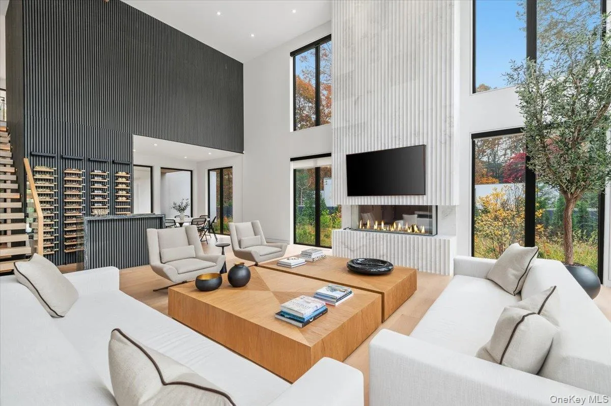 Living room with a large fireplace, a high ceiling, recessed lighting, and wood finished floors